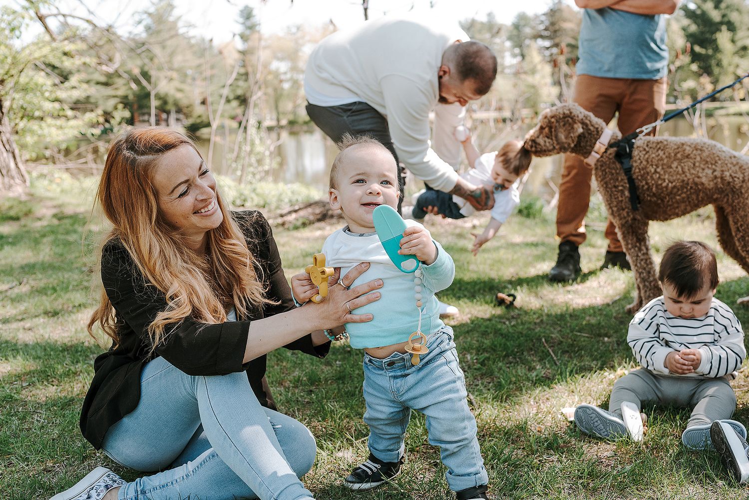 Group of families with young children gathered for outdoor playtime in a park setting.