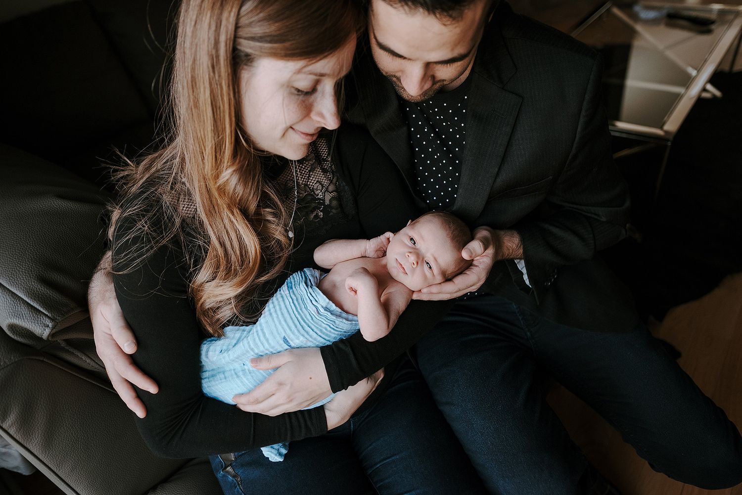 Intimate family moment with a newborn baby in a dimly lit room.