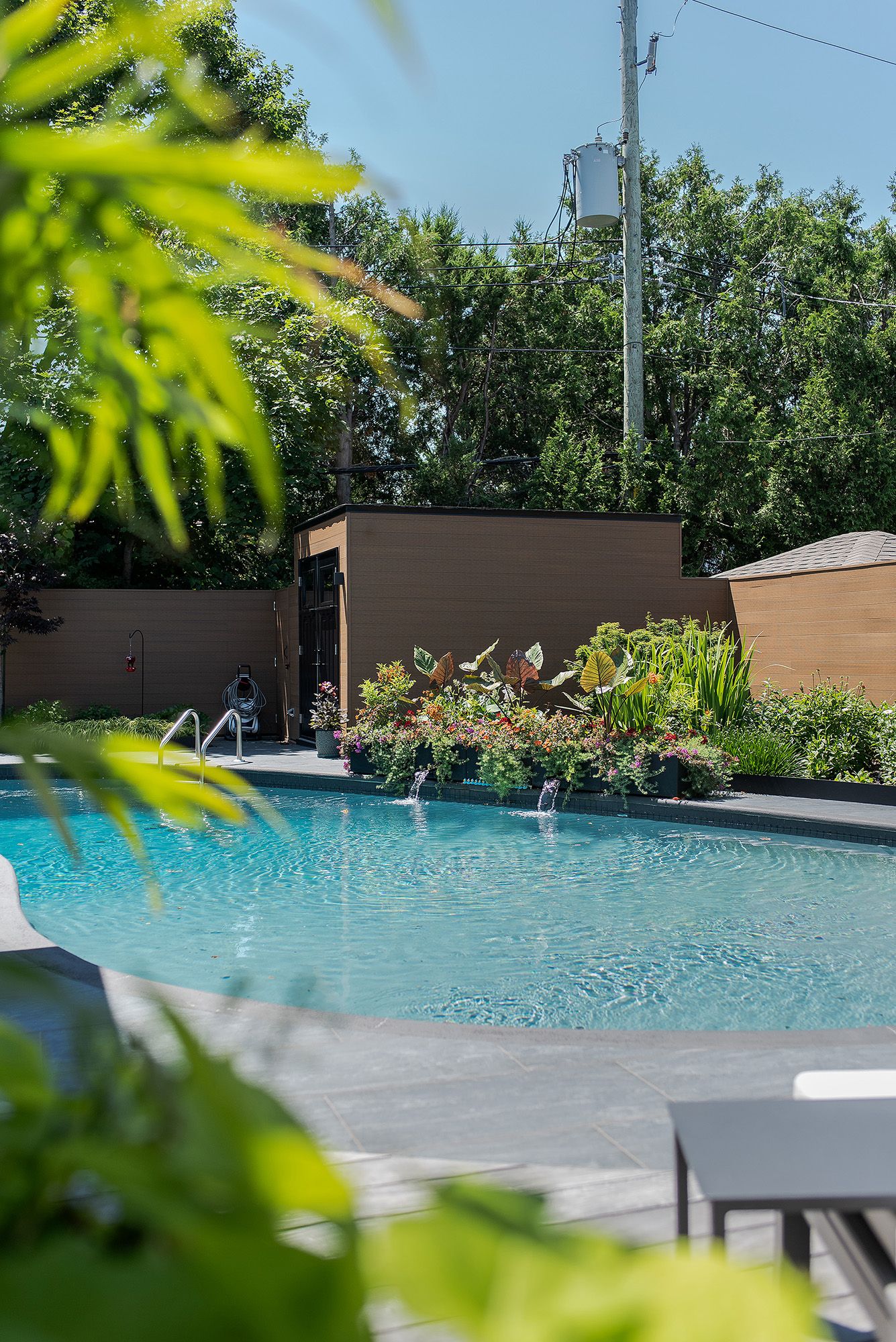 A tranquil swimming pool surrounded by lush greenery and modern landscaping features crystal clear turquoise water.