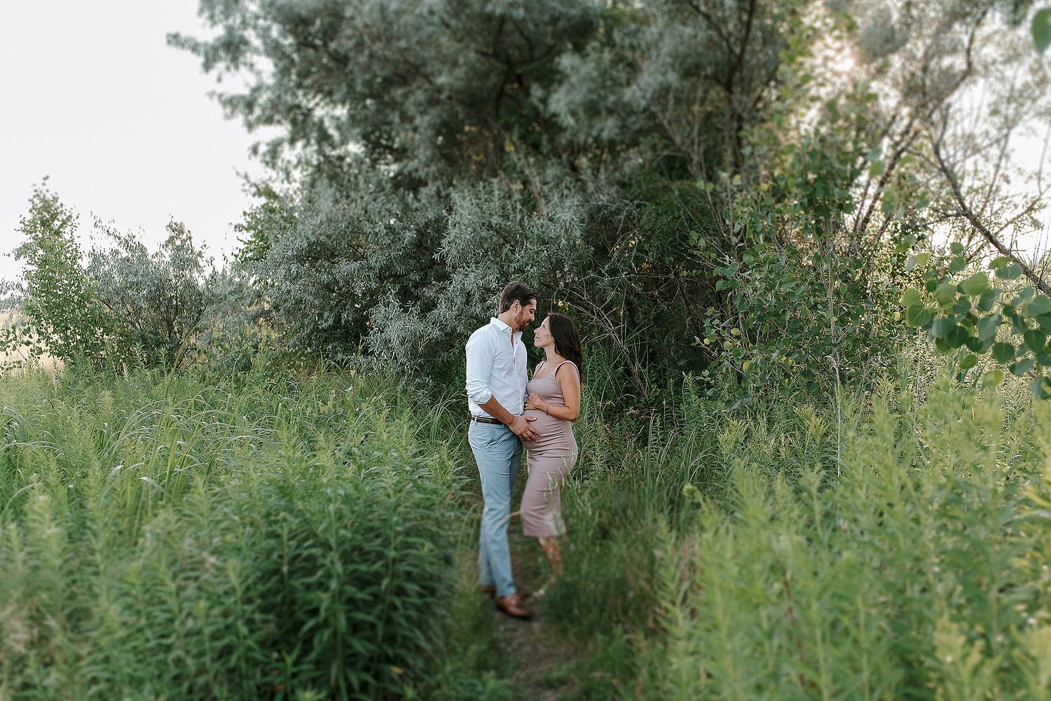 A couple shares romantic moments in a lush outdoor garden setting during a photo session.