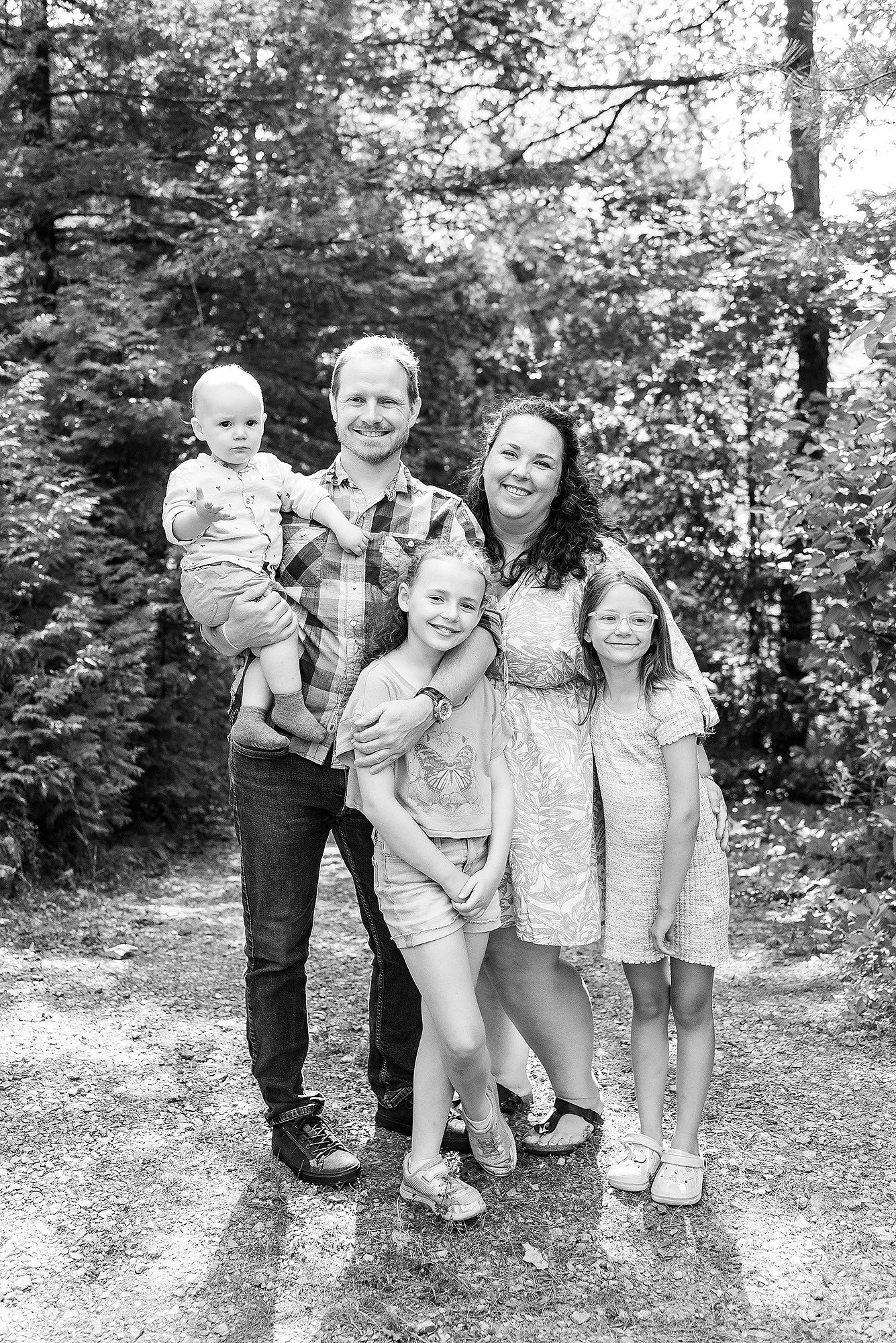 A series of black and white photos showing a group of people posing together outdoors in a wooded setting.