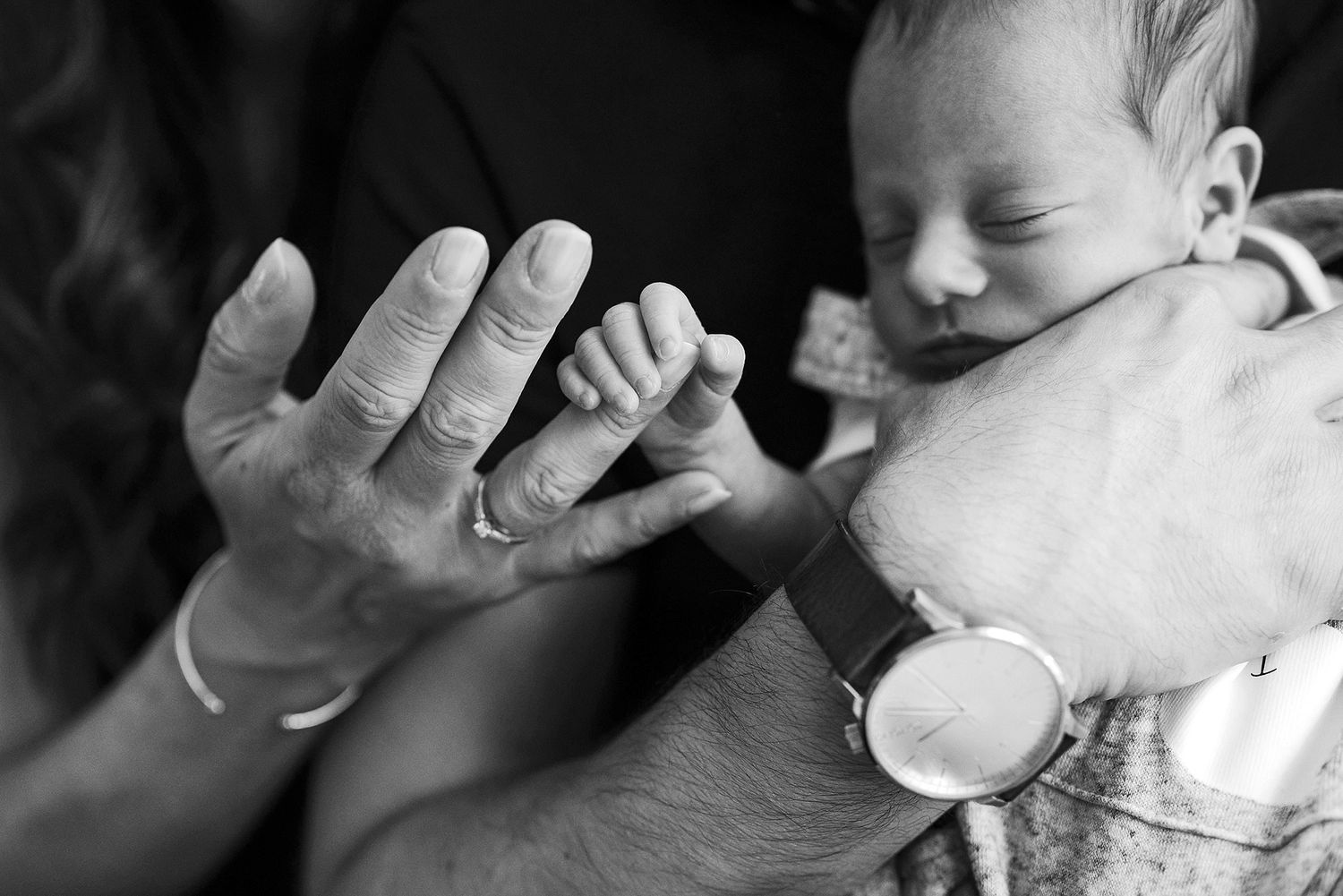 A black and white photo series showing tender moments between a baby and adult hands in various gentle interactions.