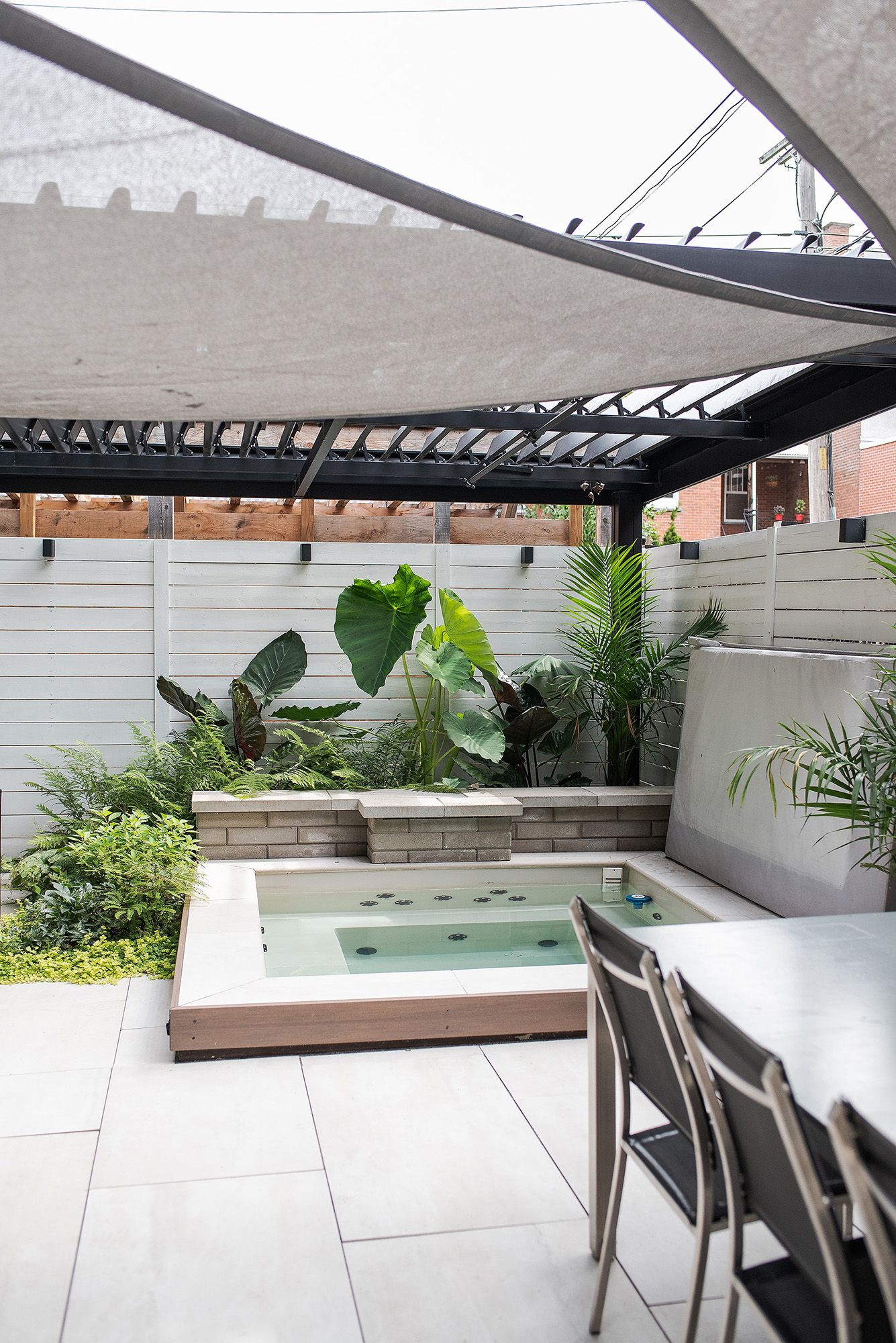 Modern outdoor patio space with white walls, sleek furniture, and tropical plants creating a contemporary urban oasis.