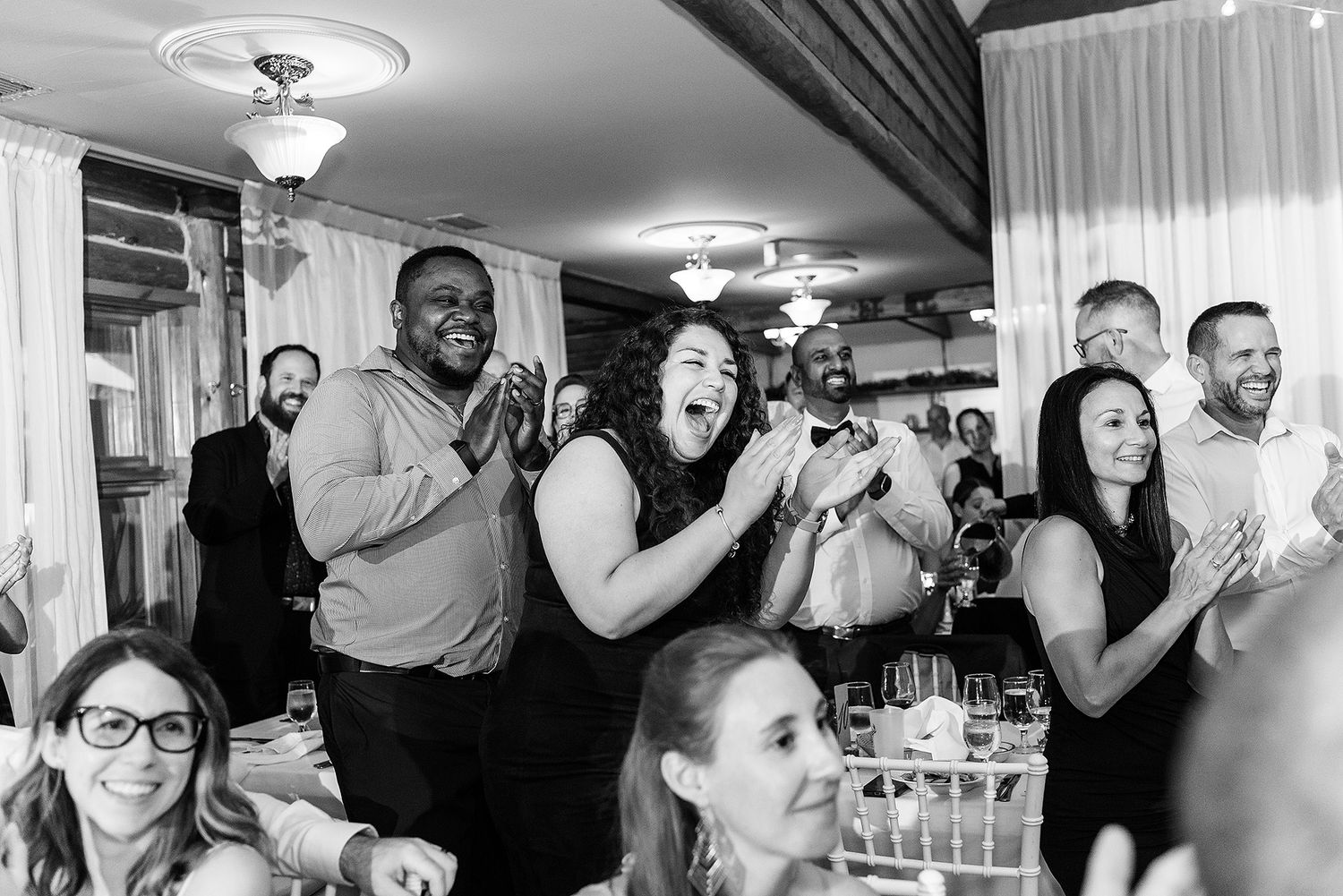 Wedding reception guests react emotionally during speeches and toasts at an indoor venue.