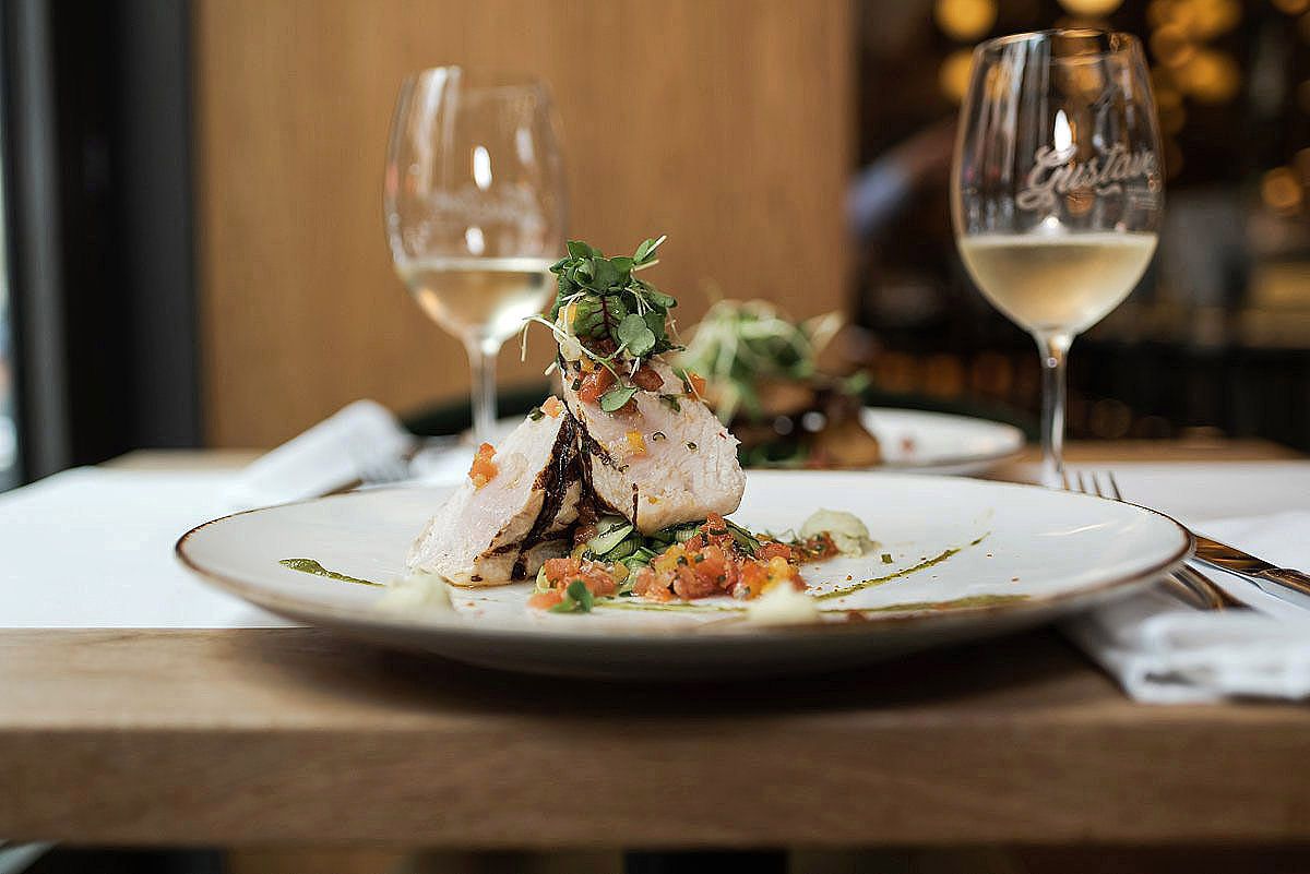 Elegant plated dishes and wine glasses on a wooden table in an upscale restaurant setting.