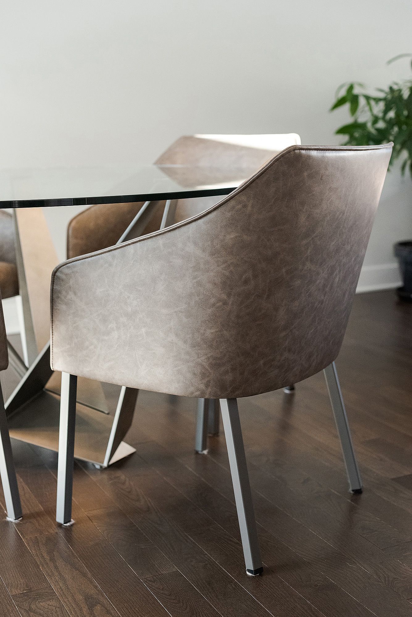 Modern gray upholstered dining chairs with metal legs arranged on dark hardwood flooring.