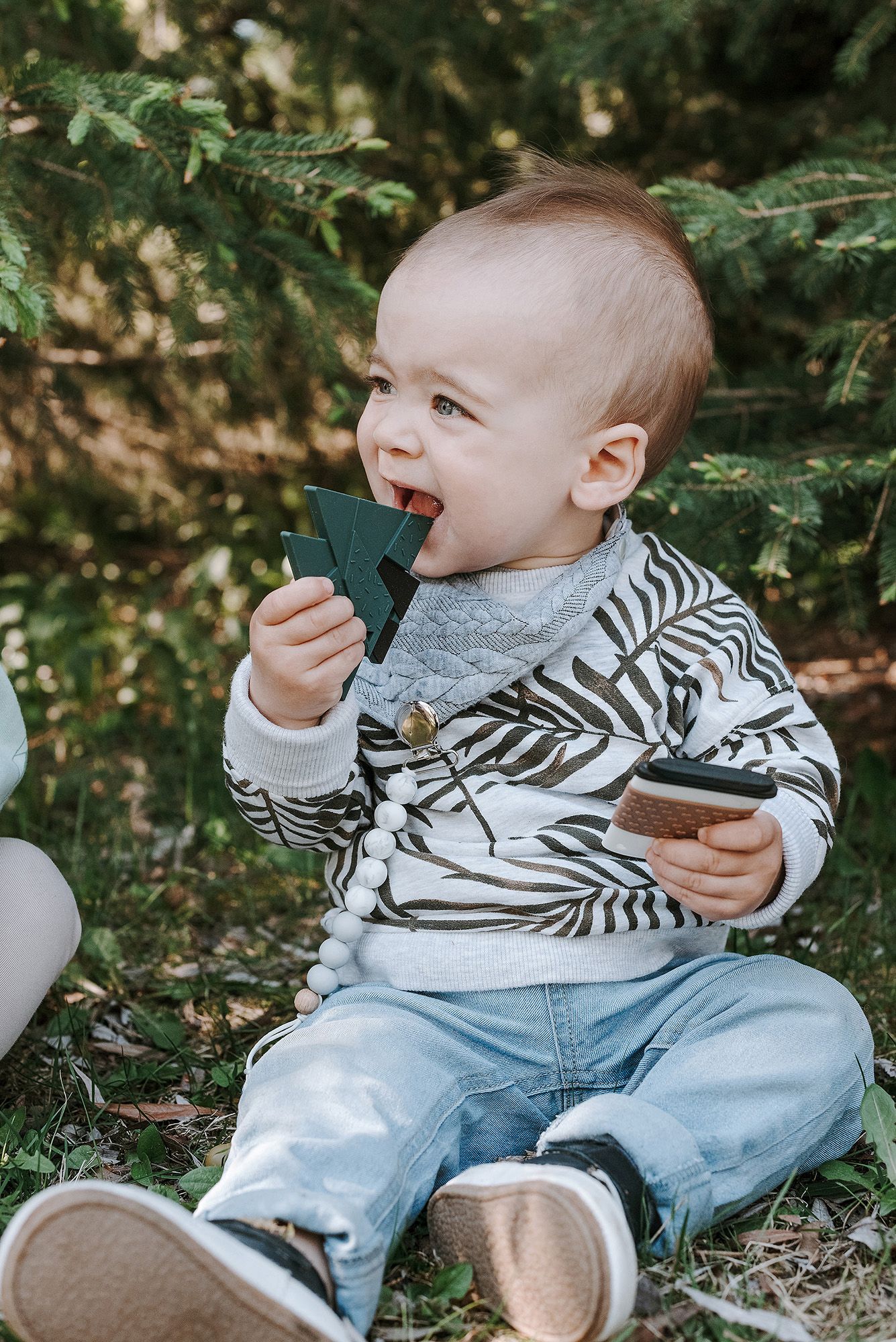 Child in striped hoodie and jeans playing with toys outdoors.