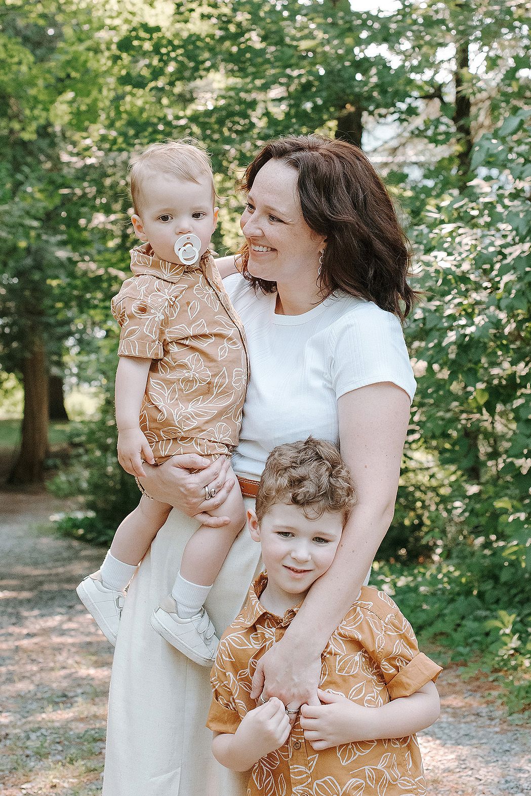 Family members sharing joyful moments together outdoors in a sunlit wooded setting.
