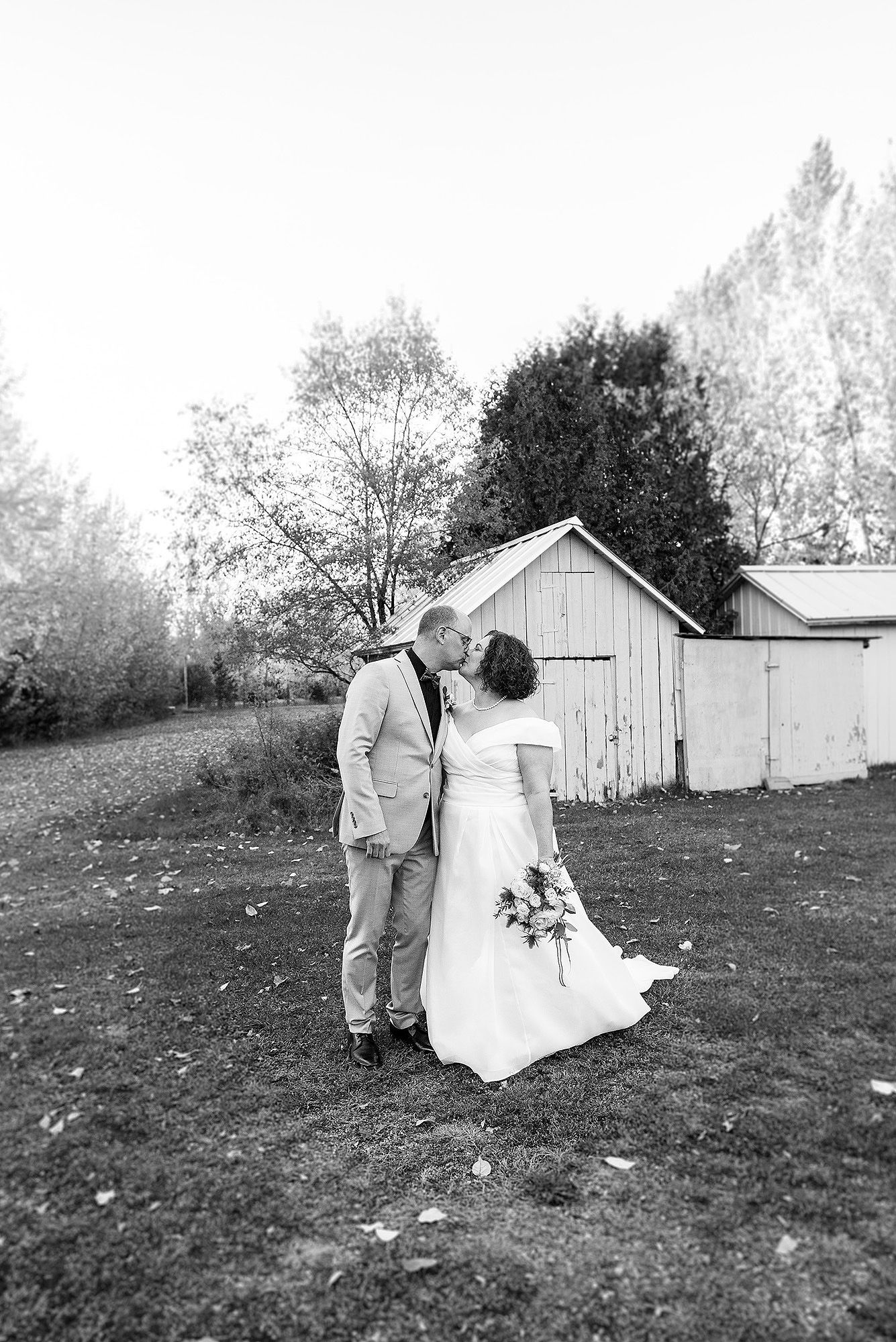A romantic black and white photo sequence of a couple walking together across a grassy field on their wedding day.