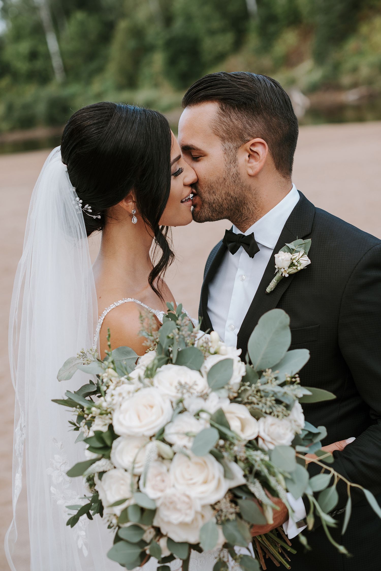 A romantic wedding portrait featuring white roses and eucalyptus in the bride's bouquet.