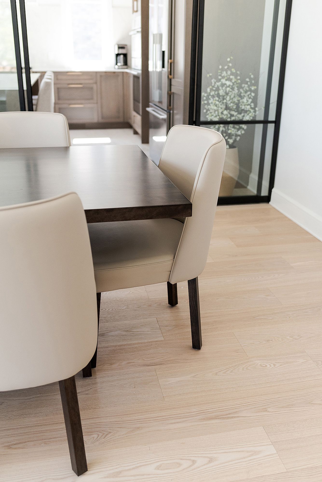 Modern dining room interior with white upholstered chairs and light wood flooring in a minimalist style.