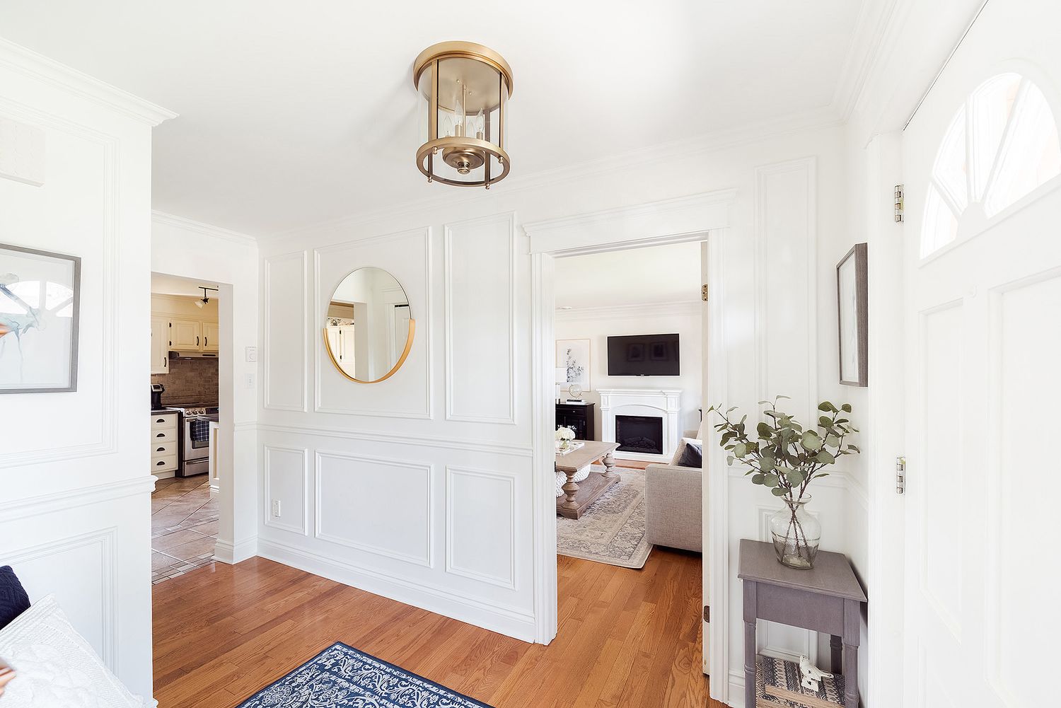 Bright and airy hallway with white walls, hardwood floors, and natural light streaming through multiple doorways.
