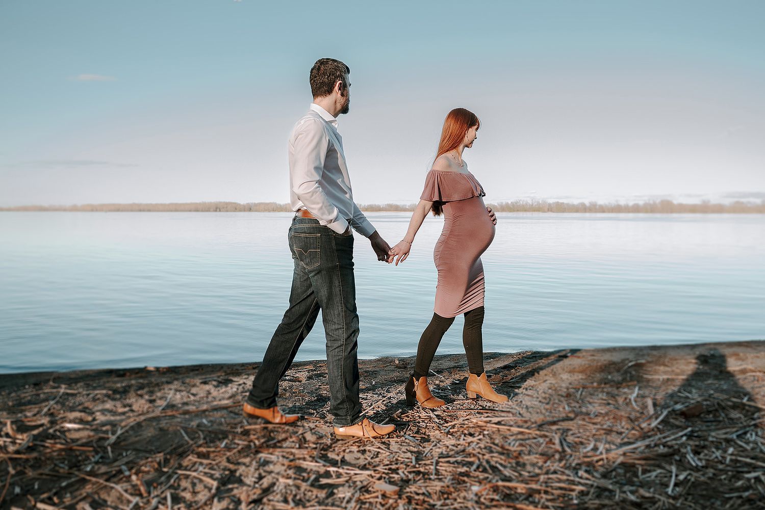 Couple walking along rocky coastline during sunset with ocean views.