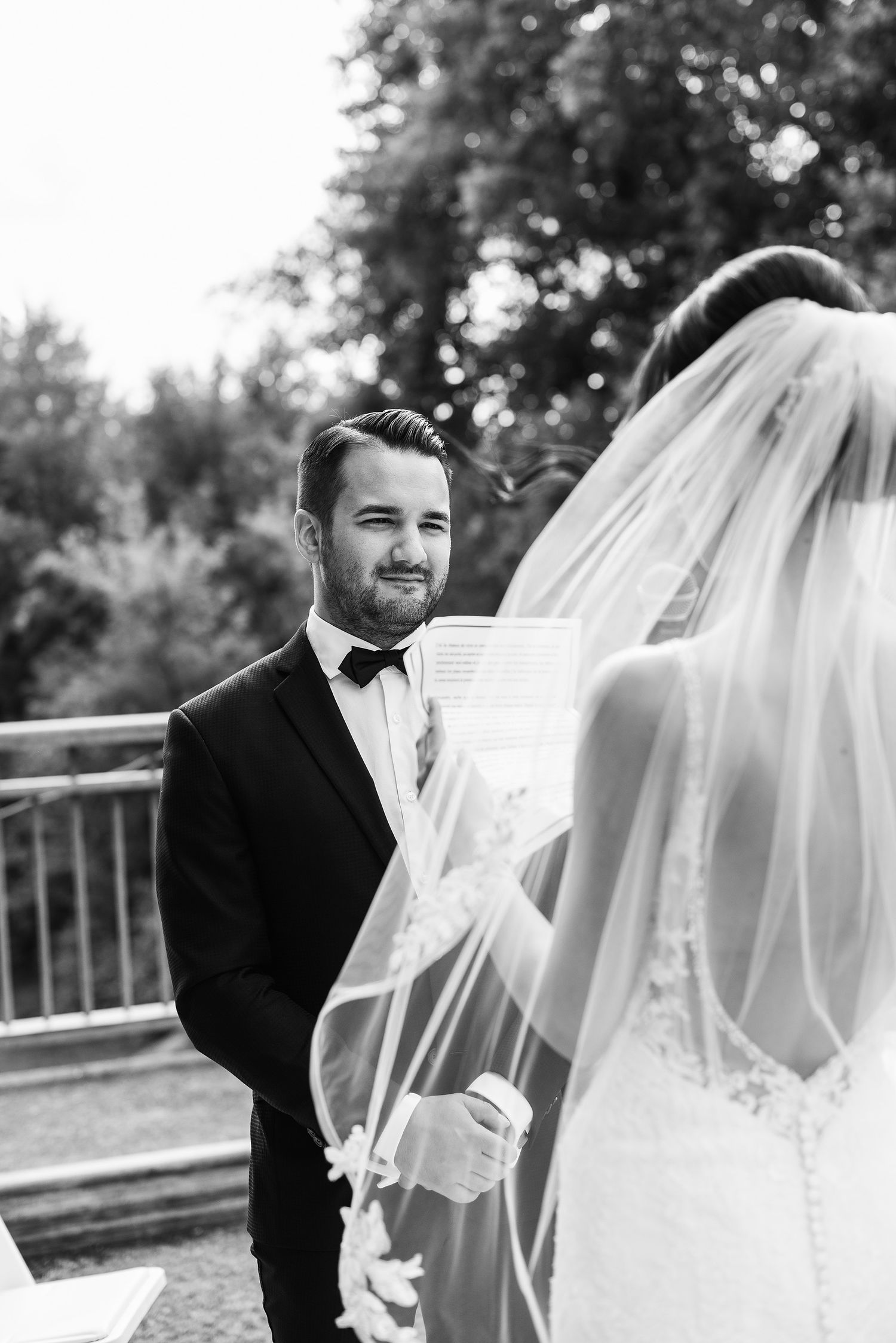 A romantic wedding sequence showing a couple sharing a first look moment through a flowing white veil outdoors.