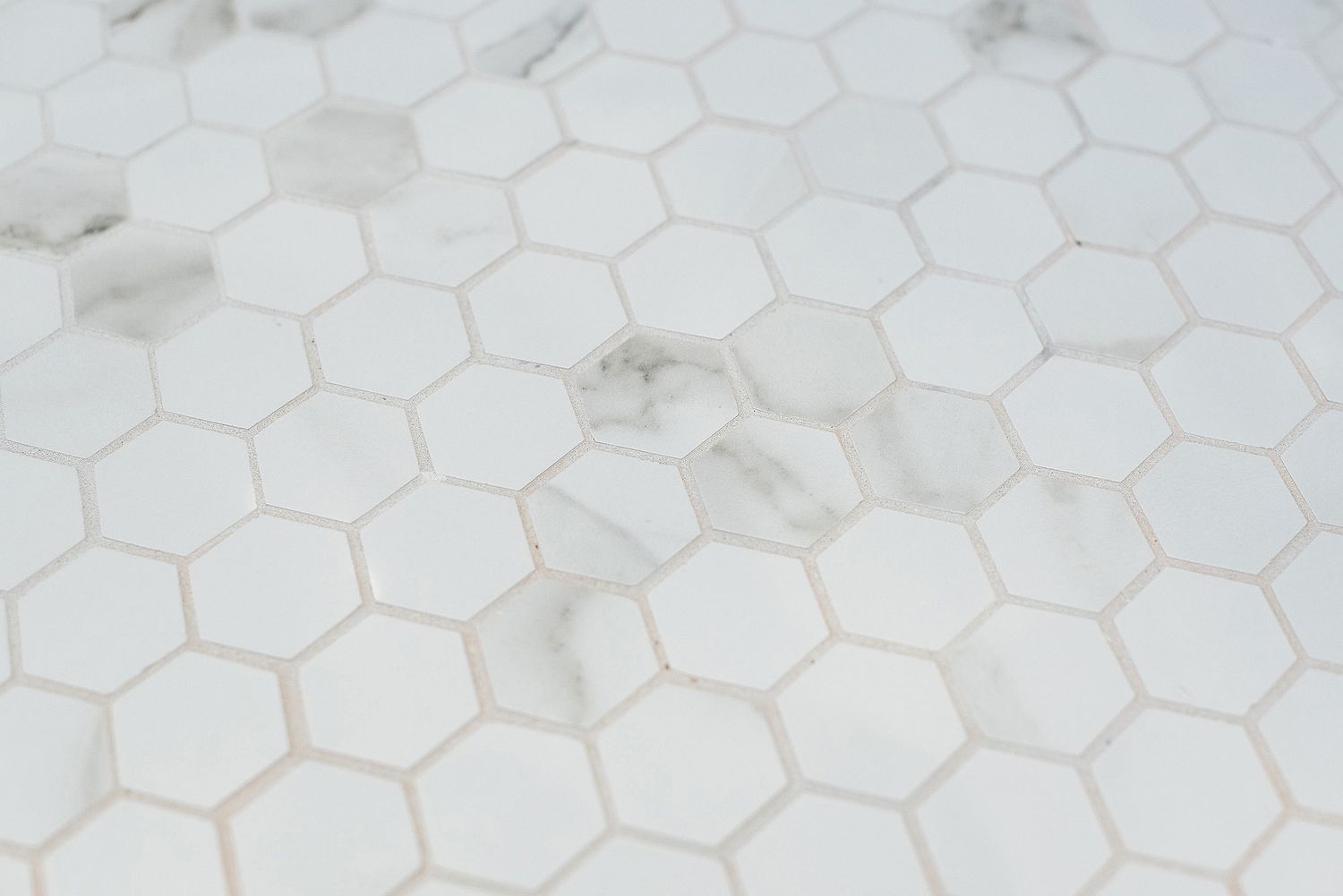 White hexagonal tile pattern with light gray grout lines creates a classic bathroom or kitchen floor texture.