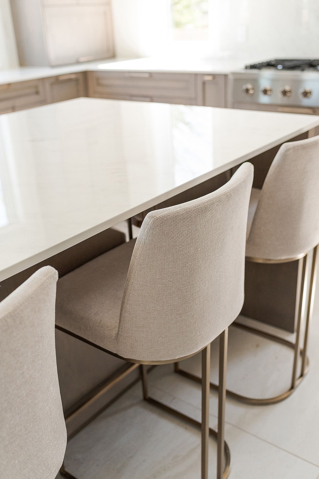 Modern dining room with curved beige upholstered chairs and sleek wooden table in a minimalist interior setting.