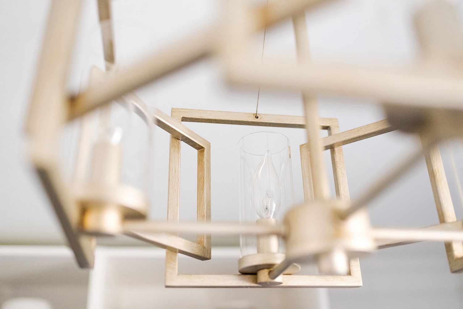 Closeup view of wooden clothespins hanging on a line against a bright blurred background.