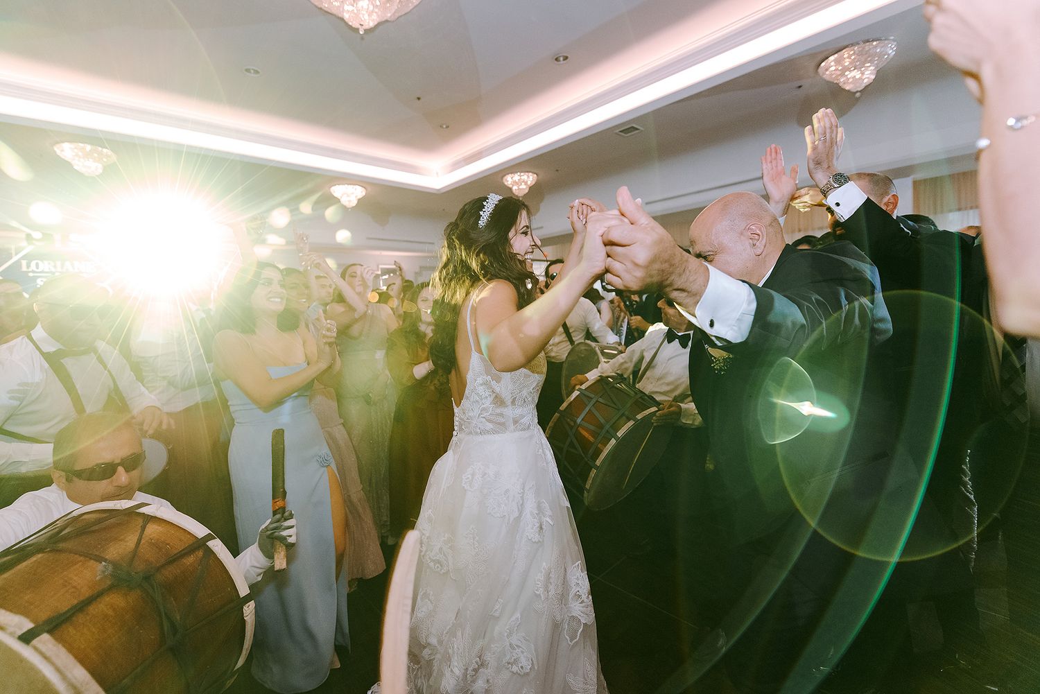 A person in a white wedding dress dances with a band performing live music at a reception celebration.