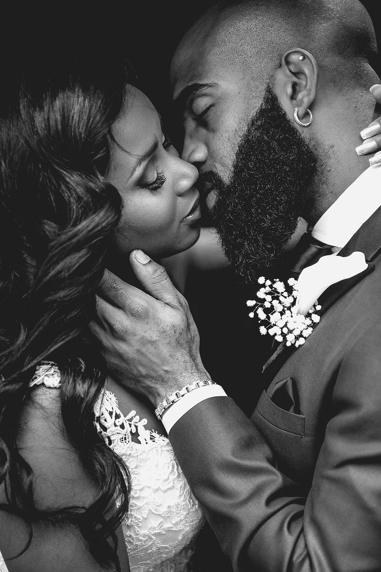Bride and groom sharing a romantic kiss in a close black and white wedding portrait.