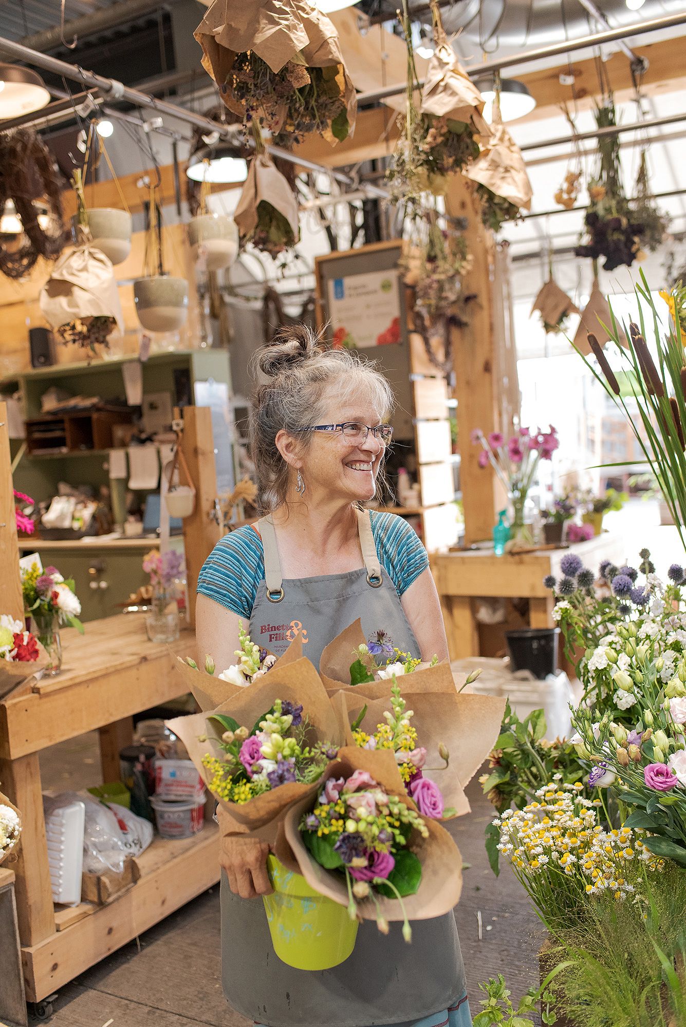 Floral workshop space with wooden shelving and hanging dried flowers creating a warm, artistic atmosphere.