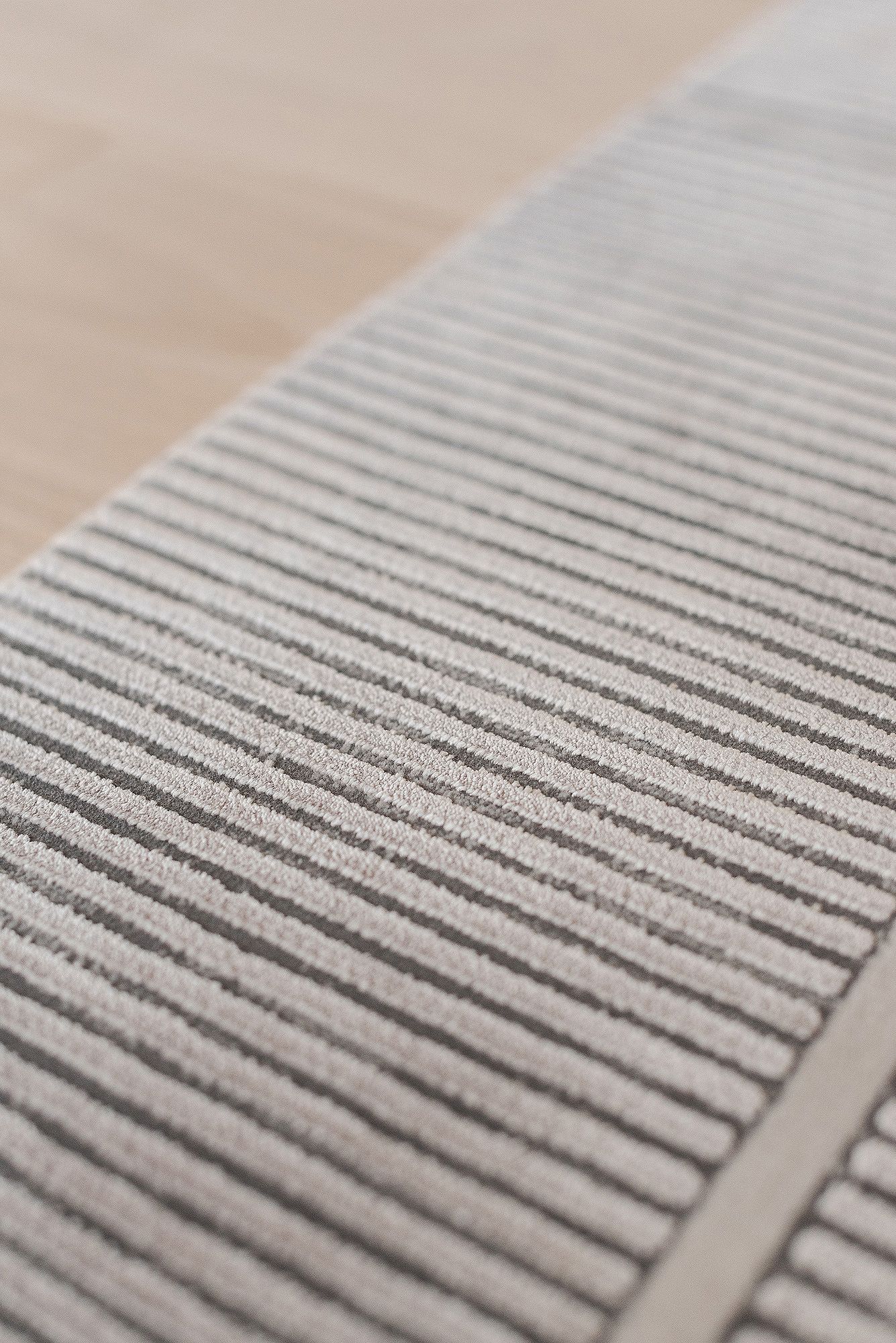 Detailed view of a gray striped carpet texture with parallel lines creating a linear pattern.