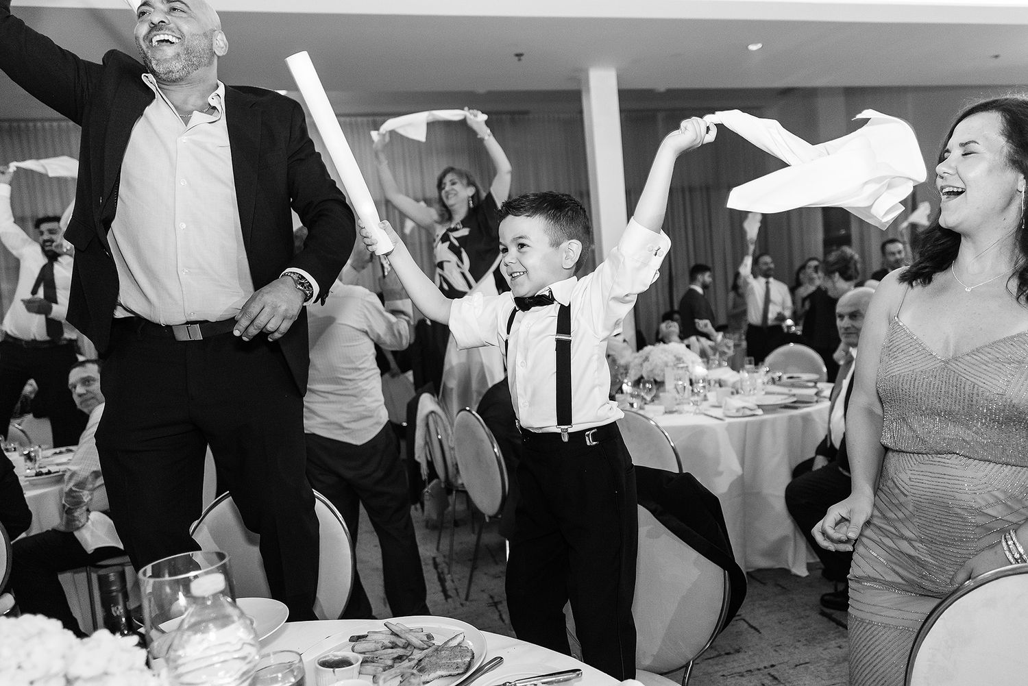 Wedding guests dance and celebrate joyfully on a crowded dance floor at a reception party.