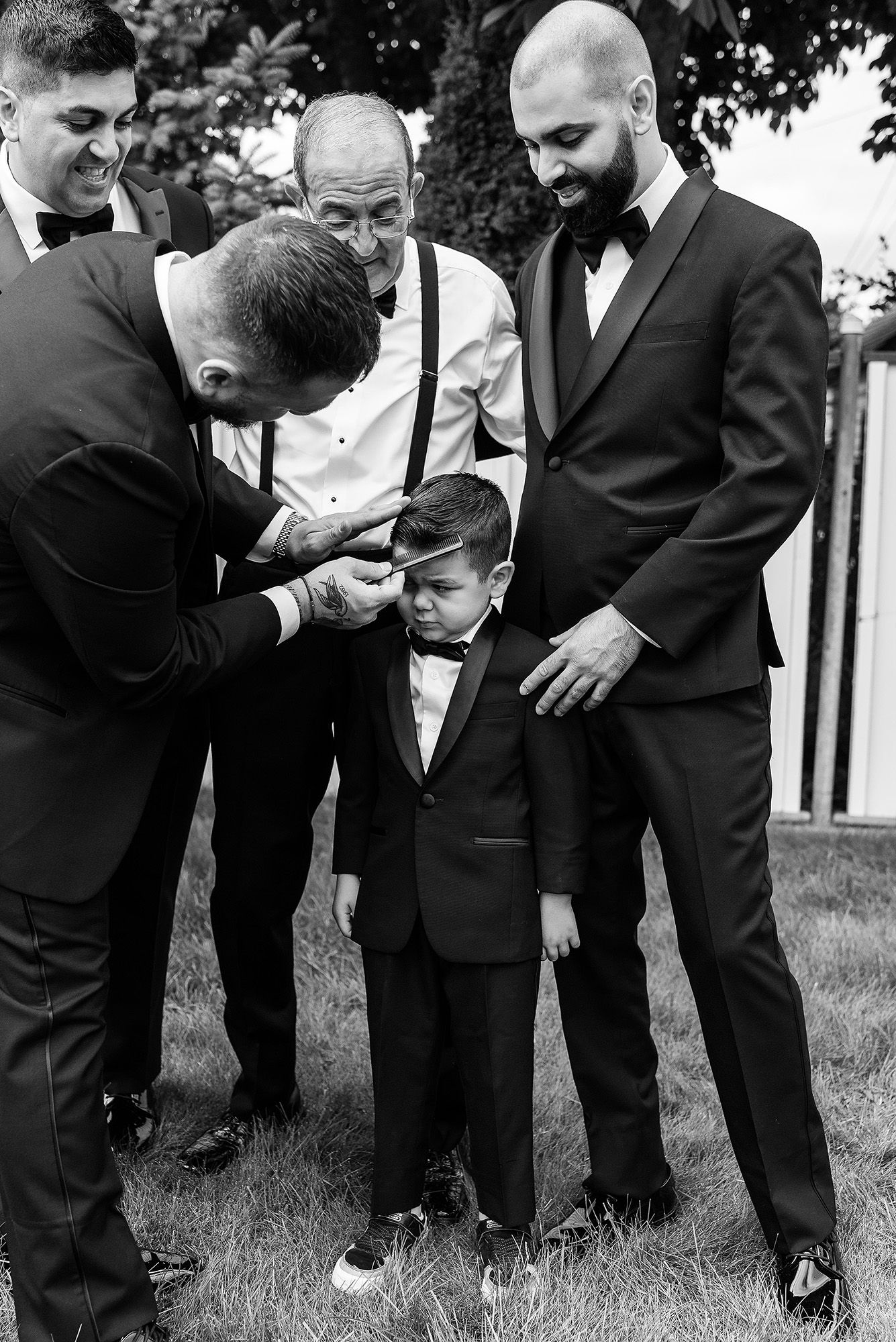 A sequence of black and white photos shows groomsmen in suits bending down to inspect a young ring bearer's attire.