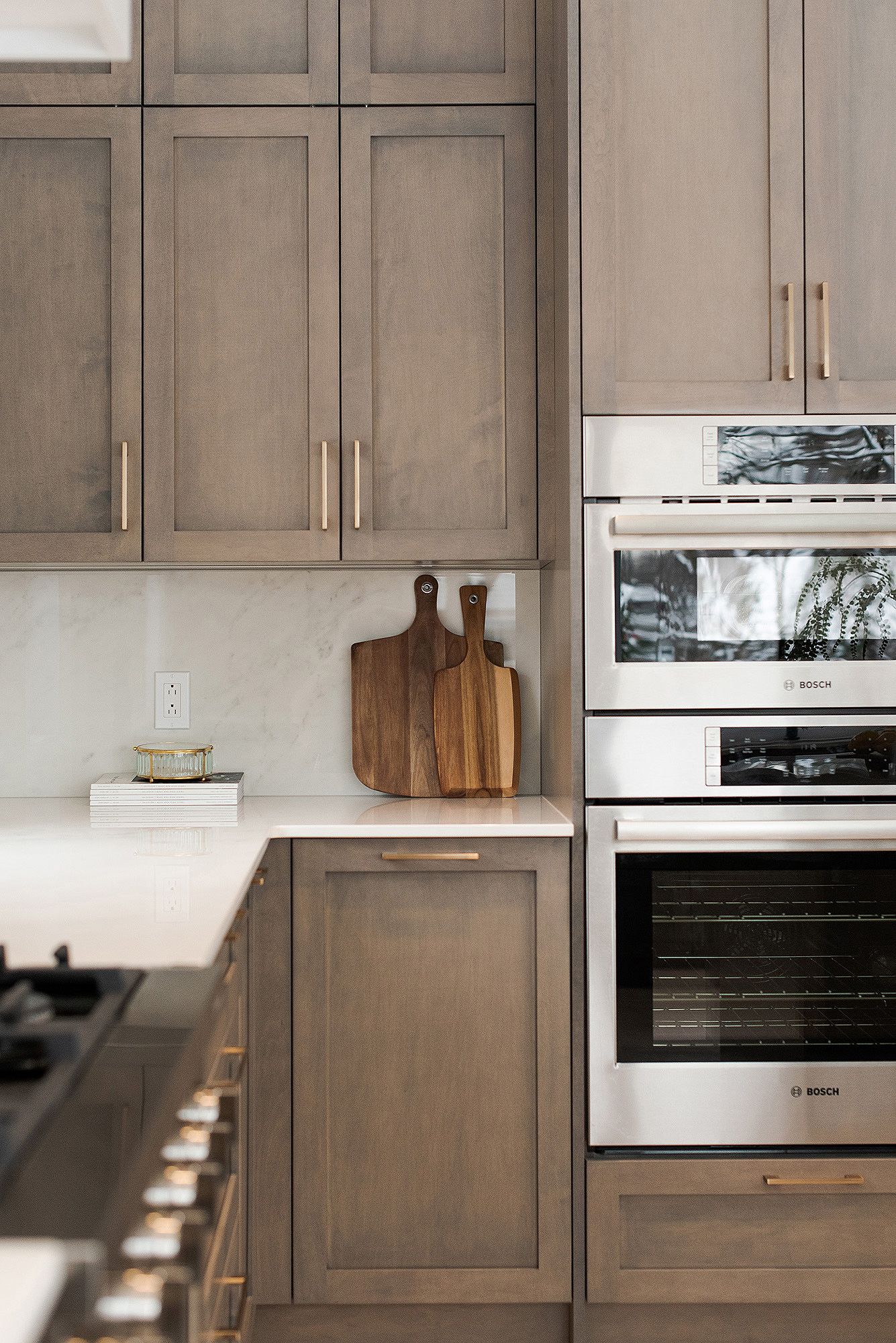 Contemporary kitchen with gray shaker cabinets, stainless steel appliances, and wooden cutting boards on counter.