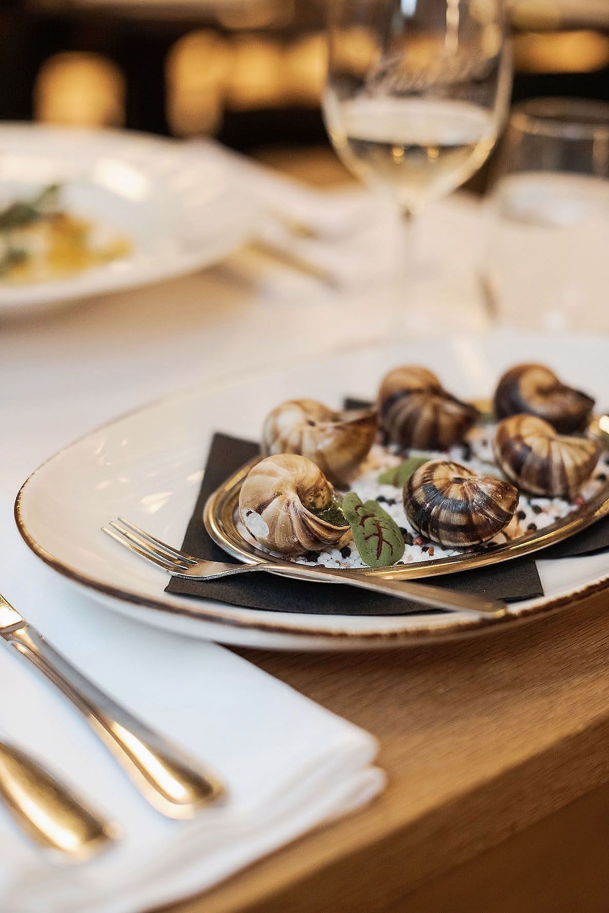 Chocolate truffles elegantly plated on white dishes with gold accents in a fine dining setting.