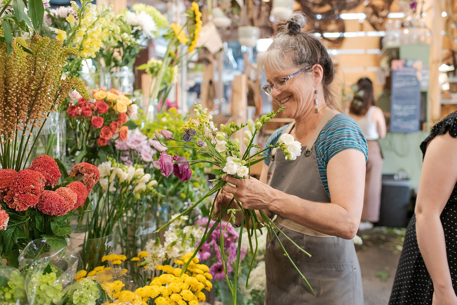 Colorful flower market stall displays vibrant blooms while shoppers browse the selection.