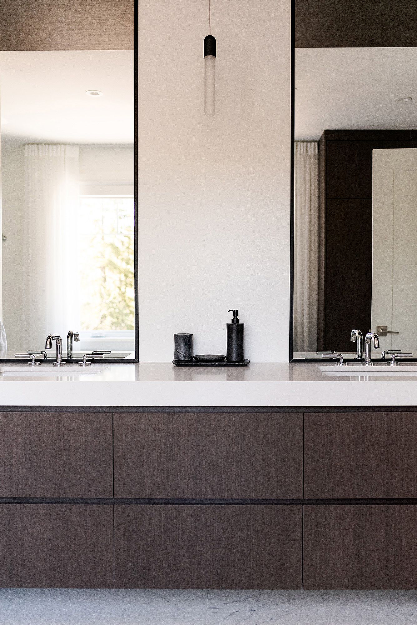 Minimalist bathroom vanity with dark wood cabinets and white countertop against white walls.