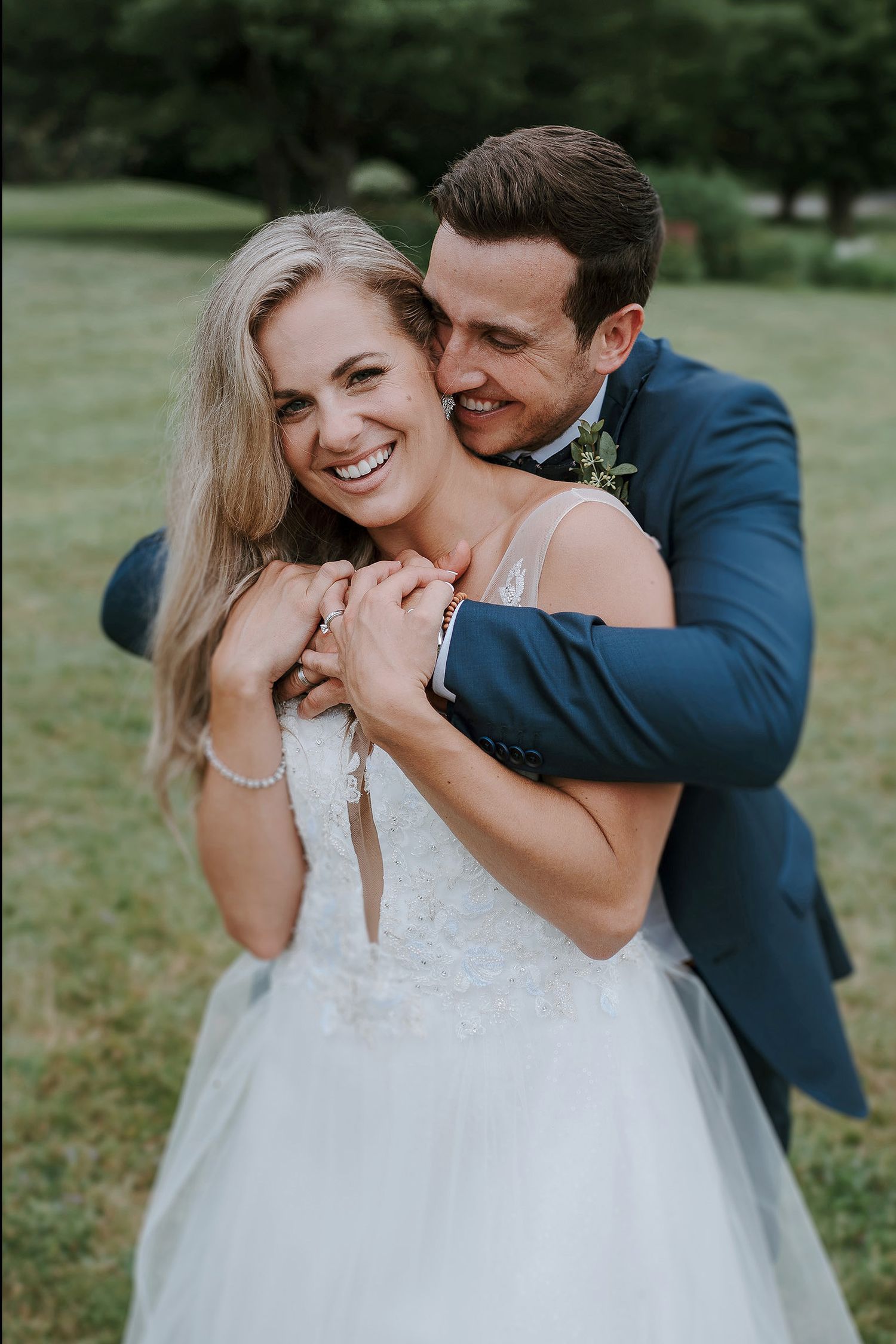 A couple shares an intimate moment in wedding attire outdoors on their special day.