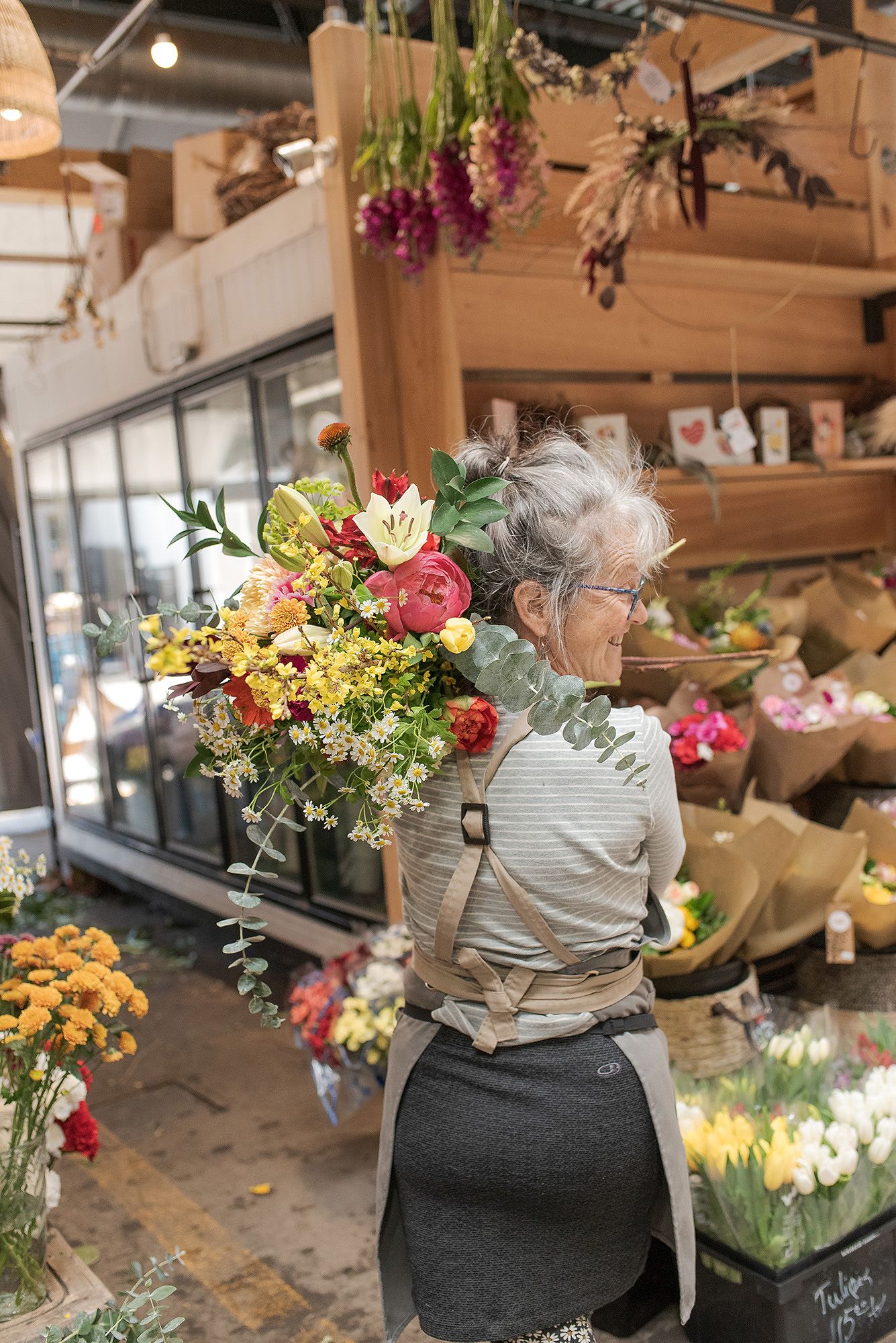 A flower shop interior with colorful bouquets displayed on wooden shelves and workstations.