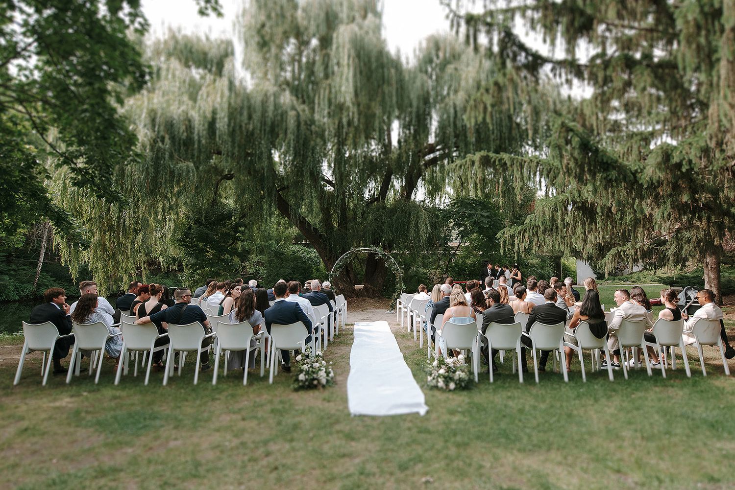 Wedding ceremony takes place under Spanish moss draped oak trees at an elegant outdoor garden venue.