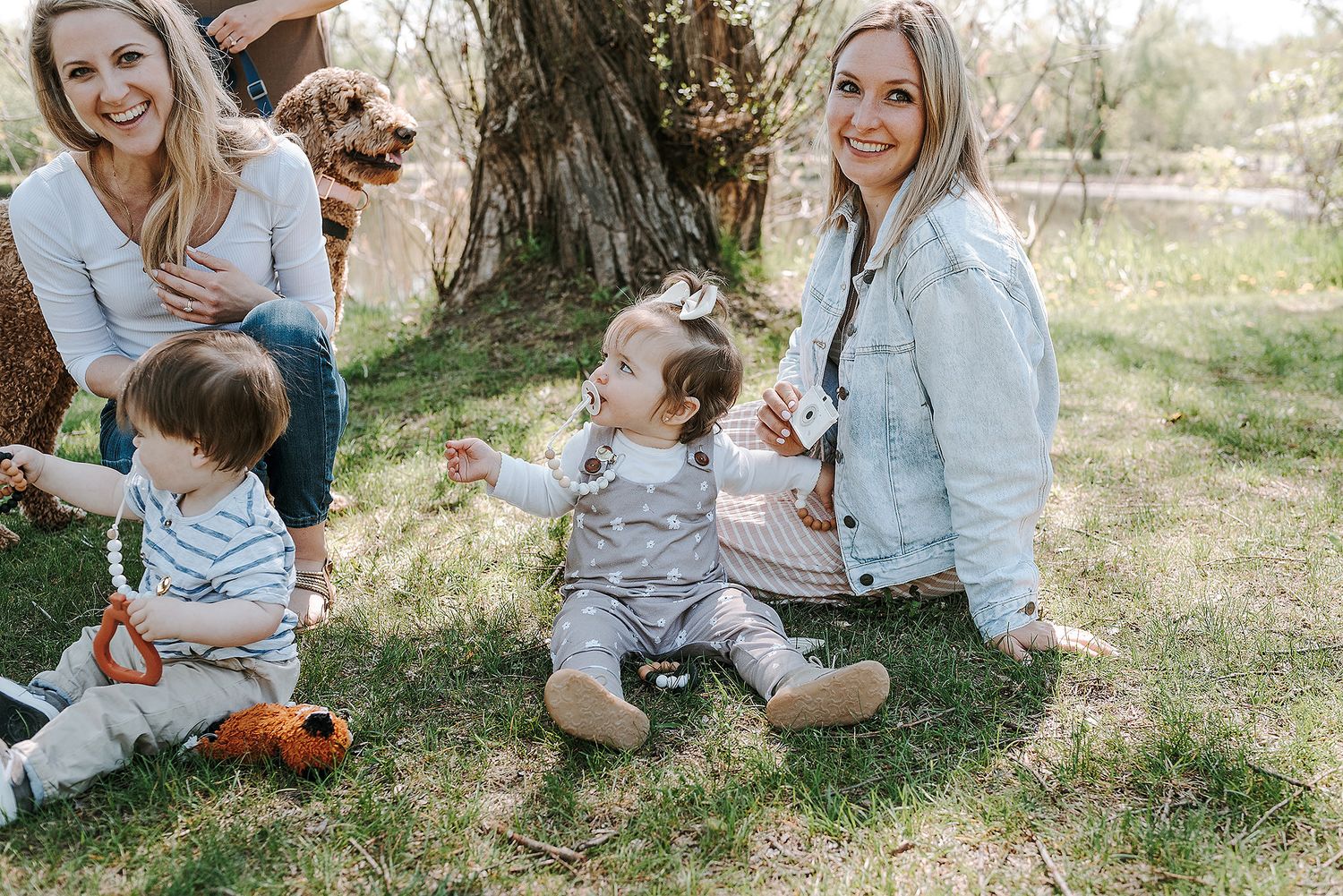 Families sitting together on grass enjoying outdoor social gathering with young children.