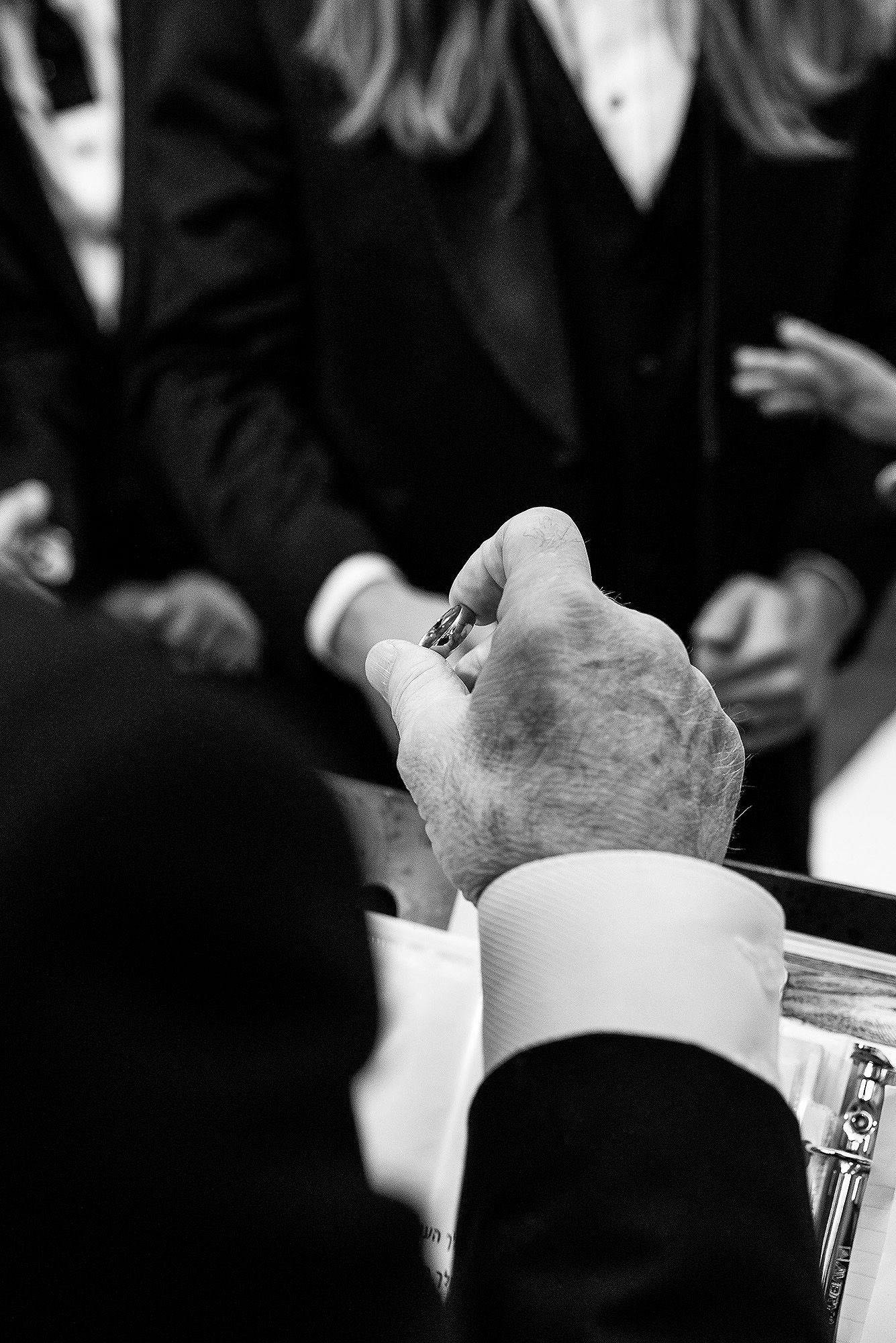 Black and white image showing hands holding paper money or currency in a dimly lit setting.