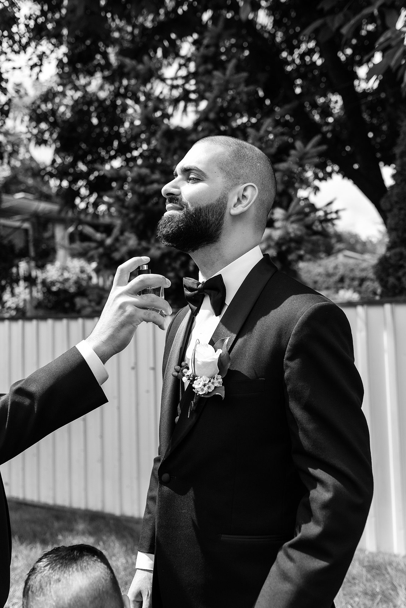 Black and white photo of groomsmen laughing and smiling together during an outdoor wedding celebration.