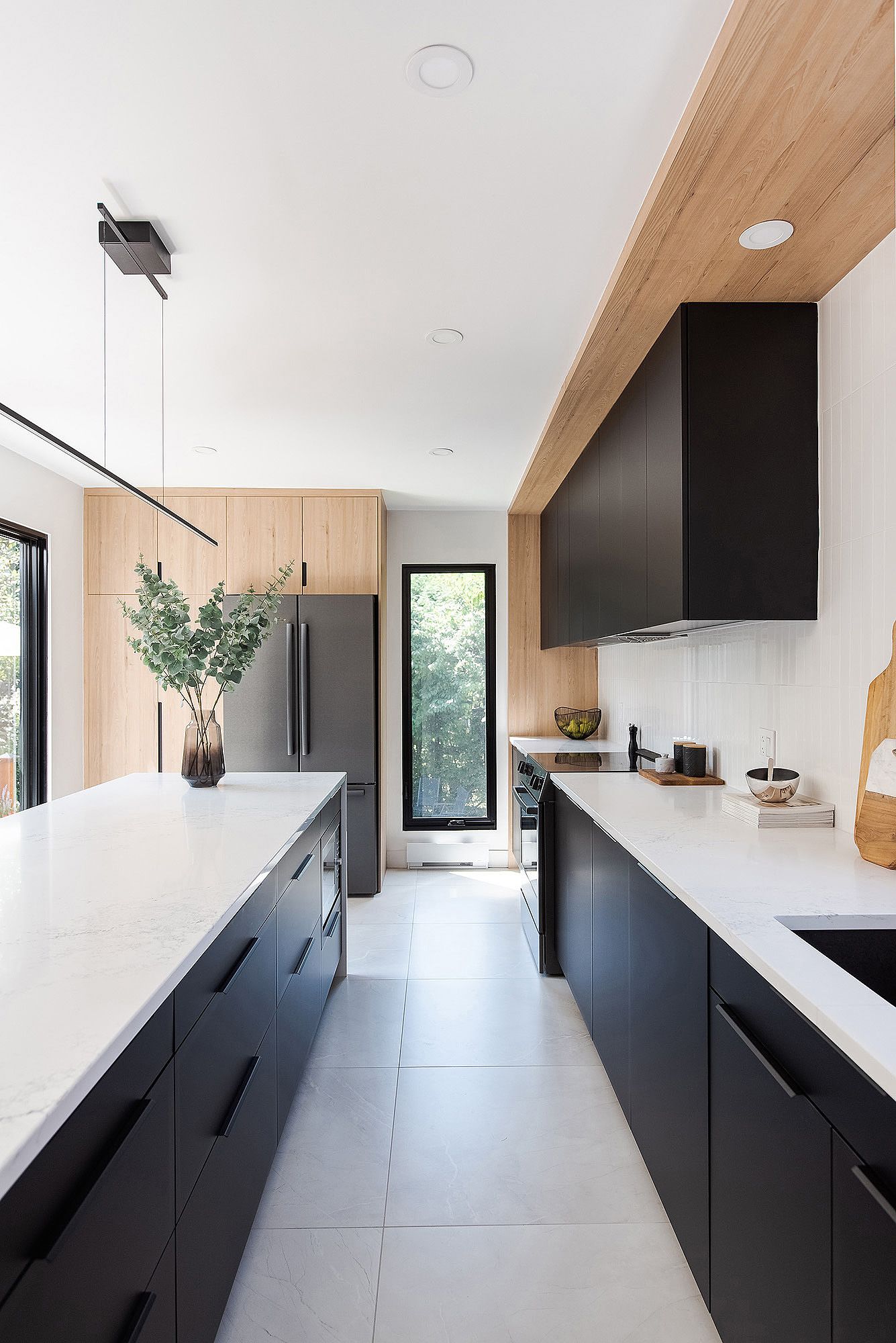 Modern kitchen with black cabinets, white countertops, and wood ceiling detail features sleek minimalist design.