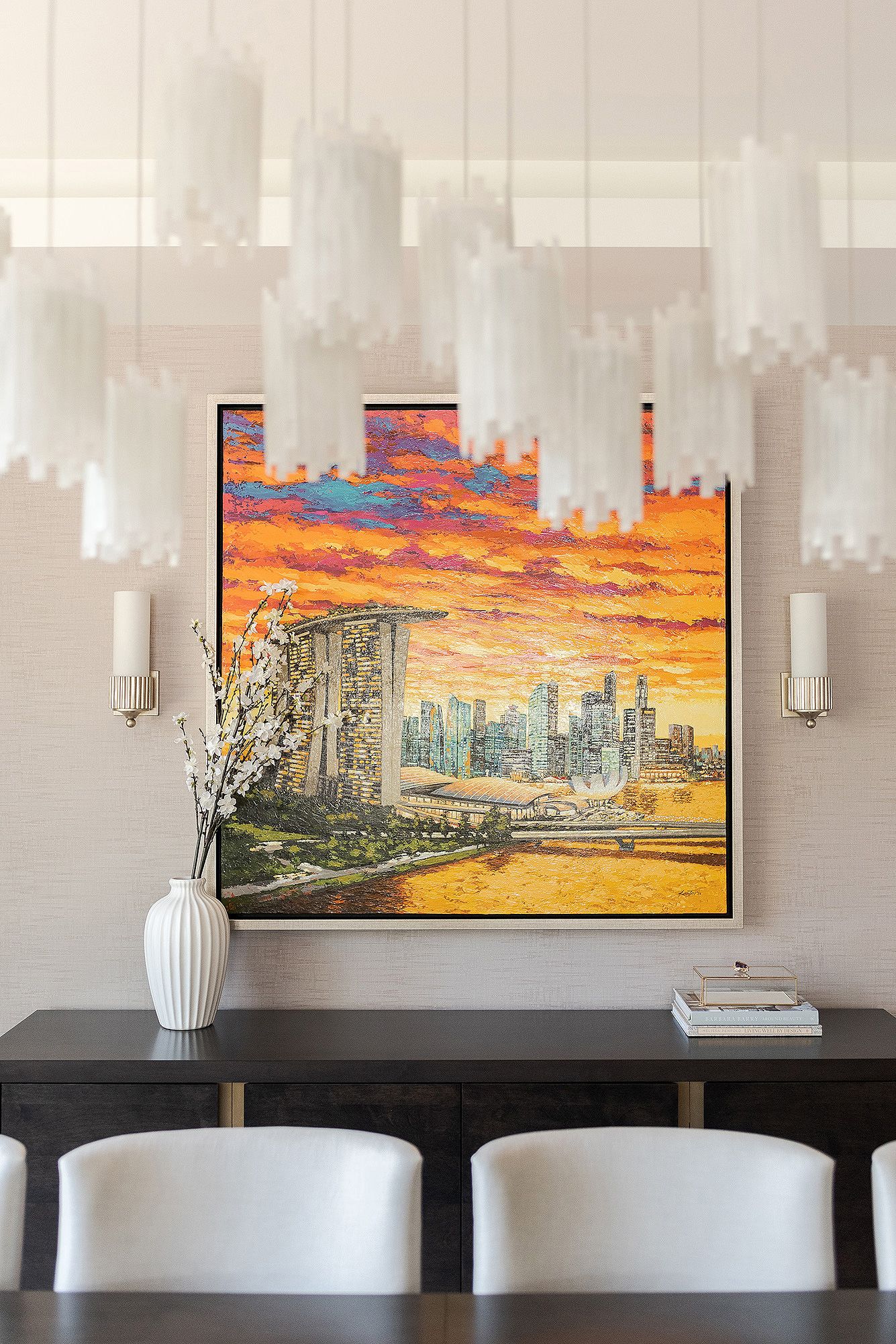 Modern living room wall features vibrant cityscape artwork with dramatic orange sunset sky above urban buildings.
