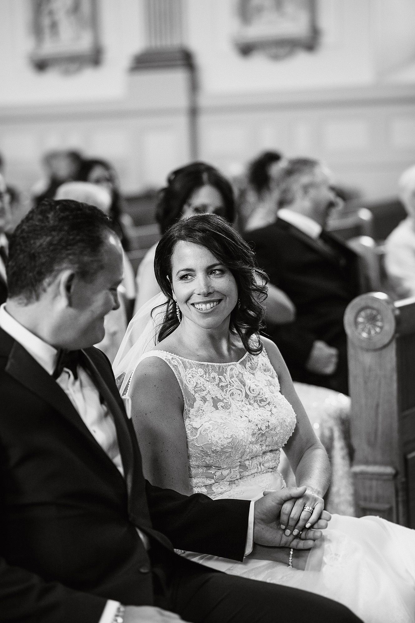 A couple shares an intimate moment during their wedding ceremony in a church pew.