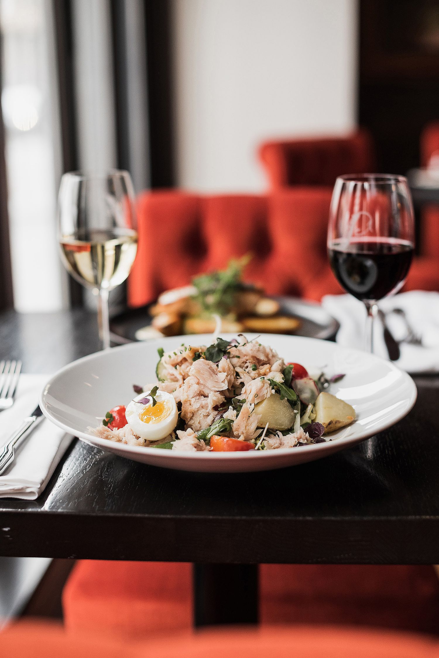 Elegant restaurant table setting with wine glasses and beautifully plated seafood dishes in soft lighting.