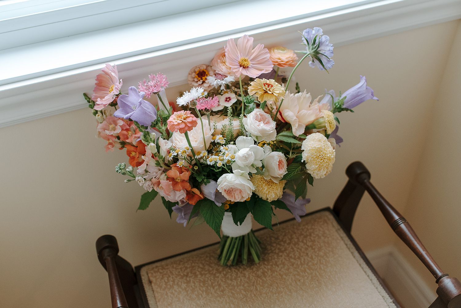 Elegant floral centerpiece with pink and white flowers in a tall vase at a wedding reception.