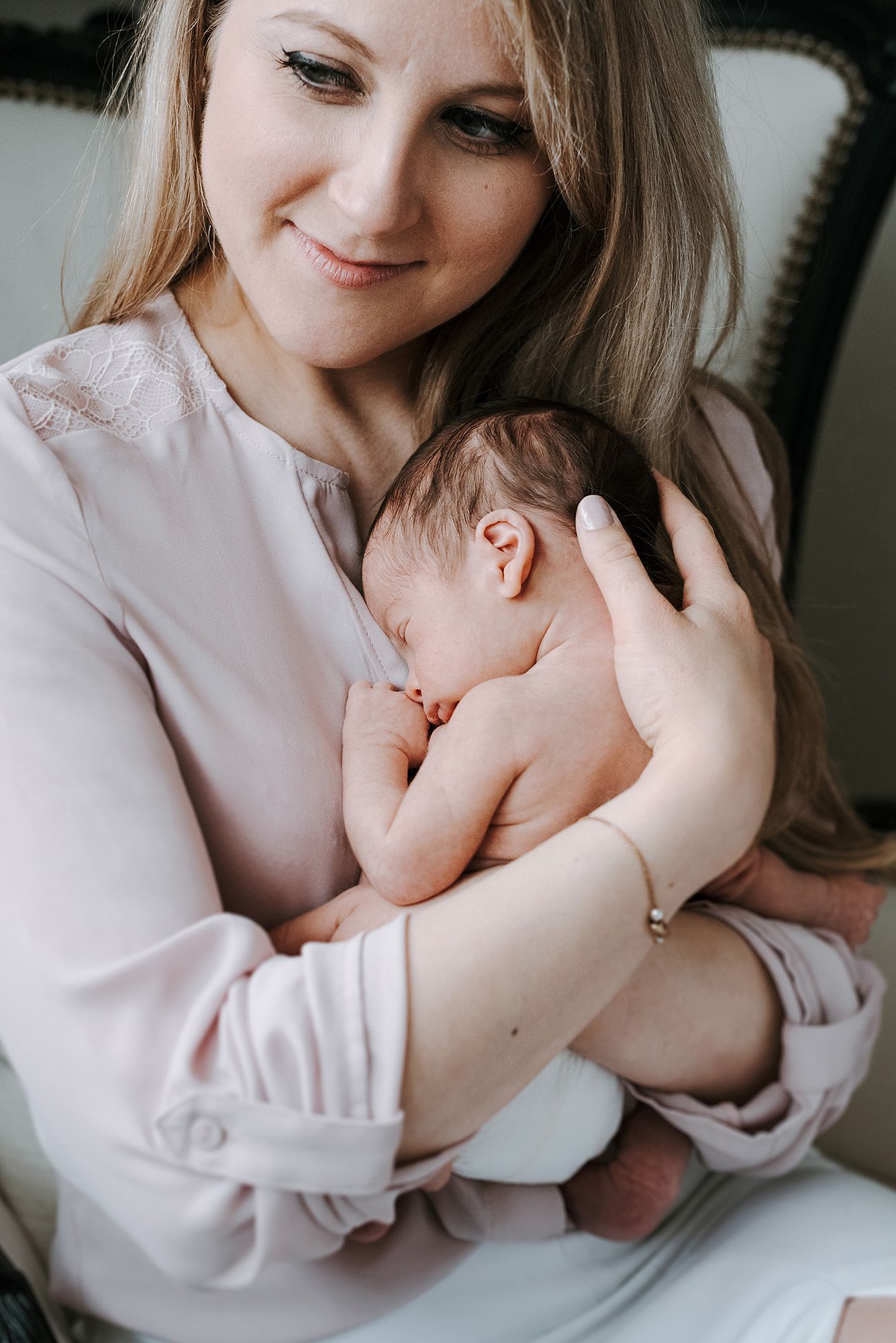 Tender moment between parent and newborn in soft natural light.