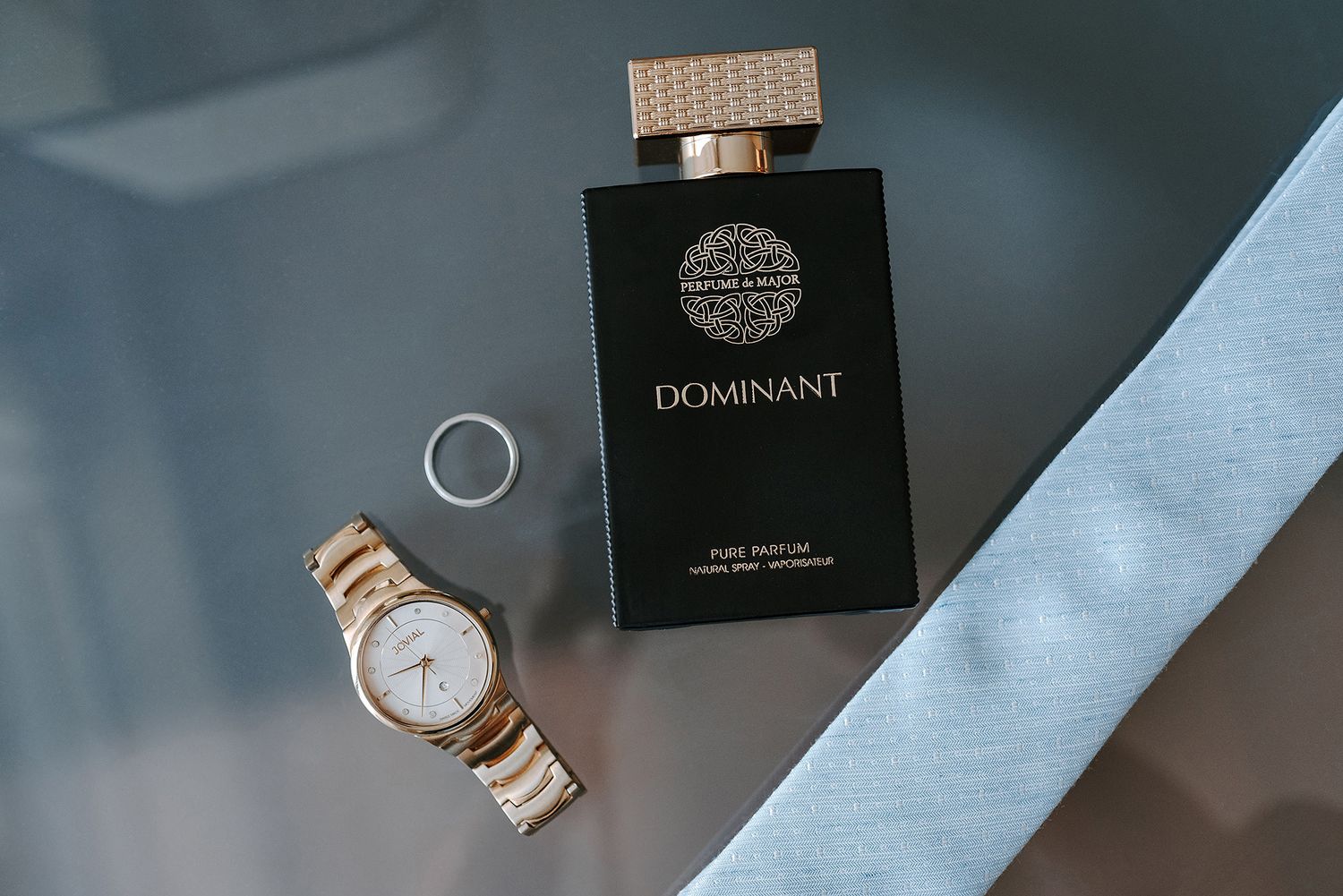 Elegant watch and perfume bottle arrangements on a dark surface with moody lighting.