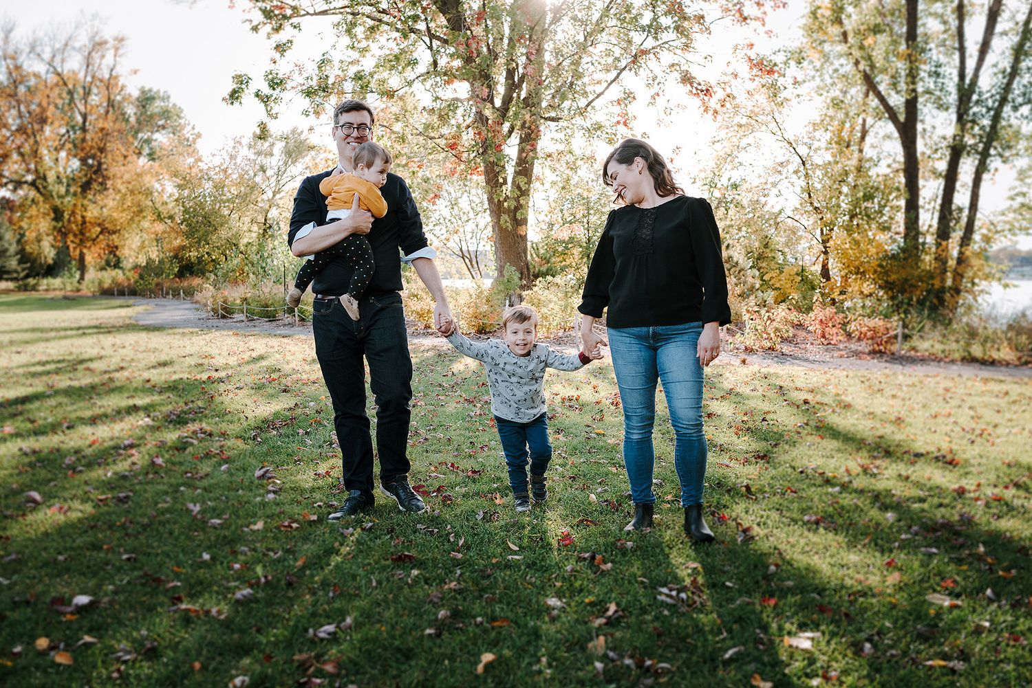 Family walking together on grass path during golden hour in autumn.