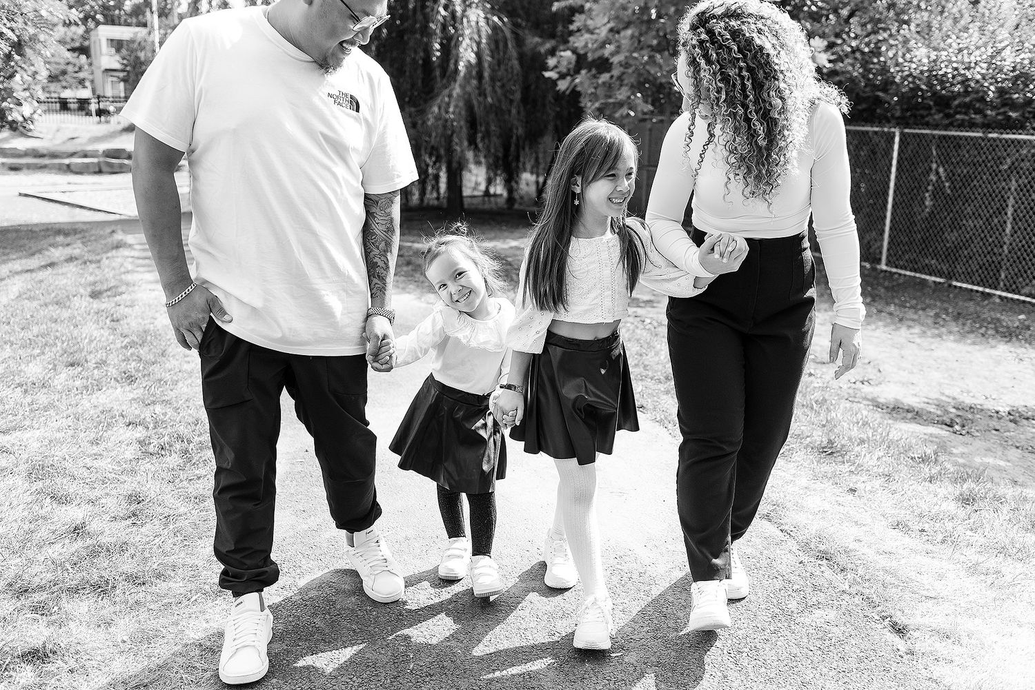 Black and white family portraits captured outdoors on a sunny afternoon.