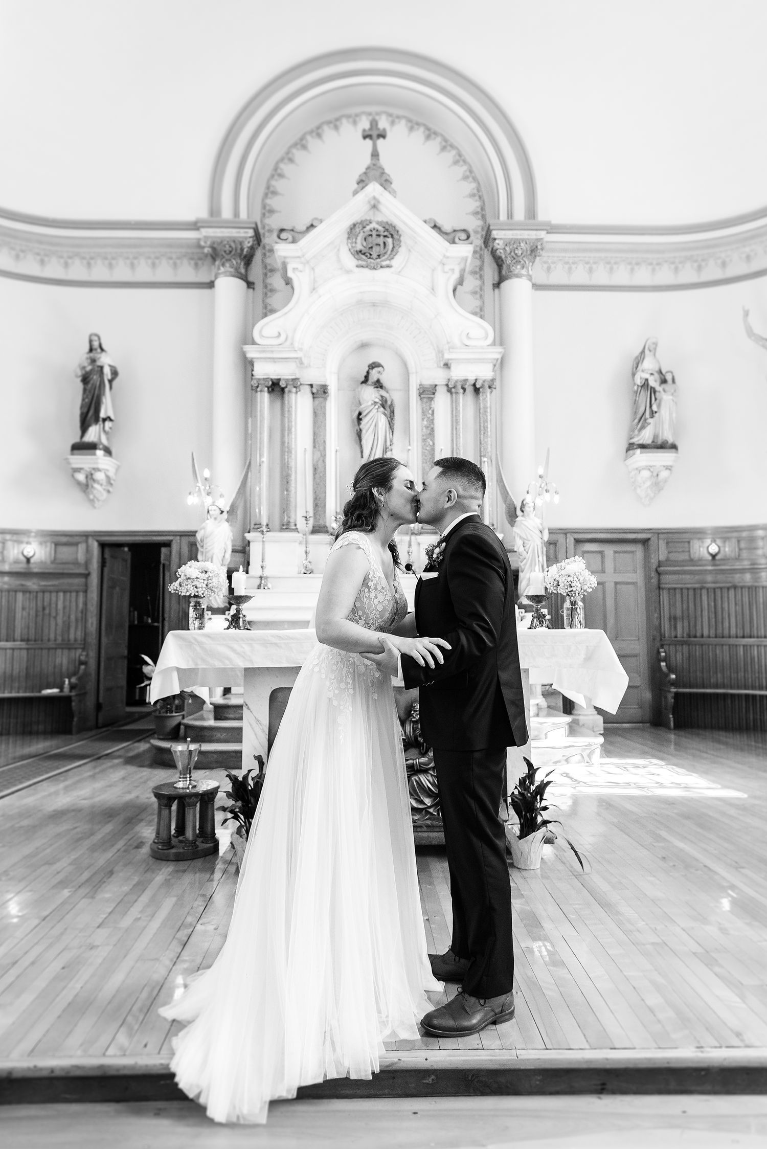 A romantic wedding ceremony in a historic church with ornate white walls and religious statues.