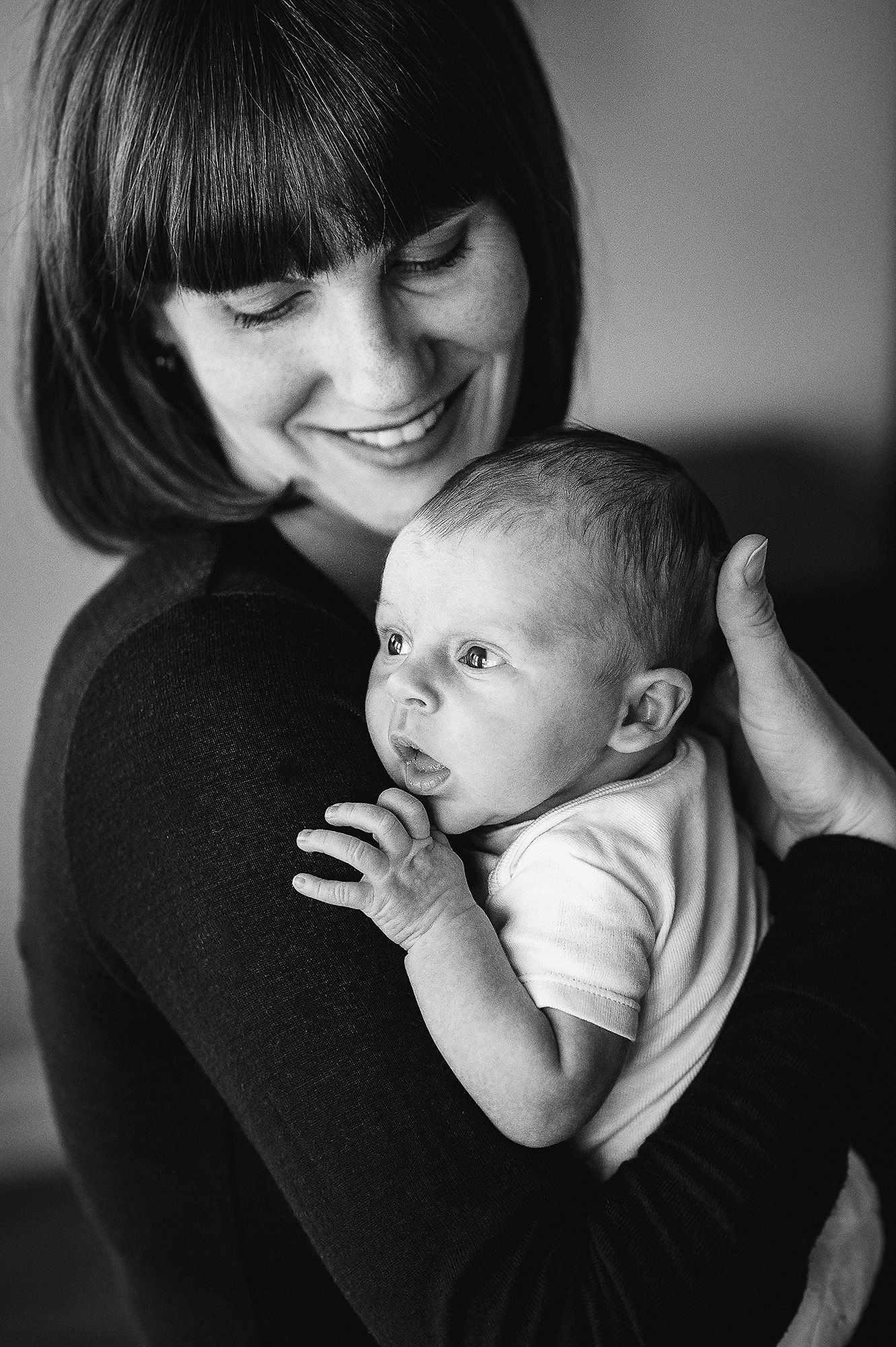 Black and white portrait series of a parent holding and bonding with their newborn.