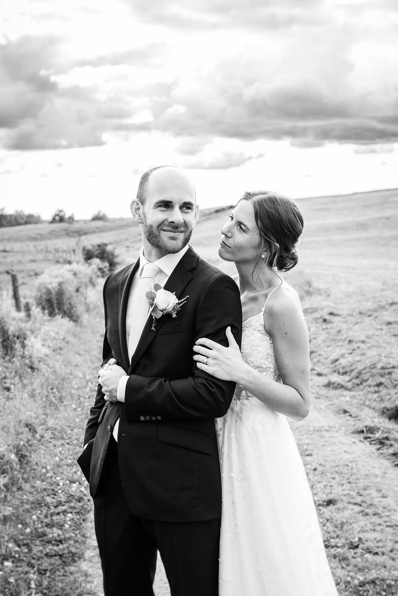 Black and white portrait of newlyweds sharing an intimate moment in an open field.