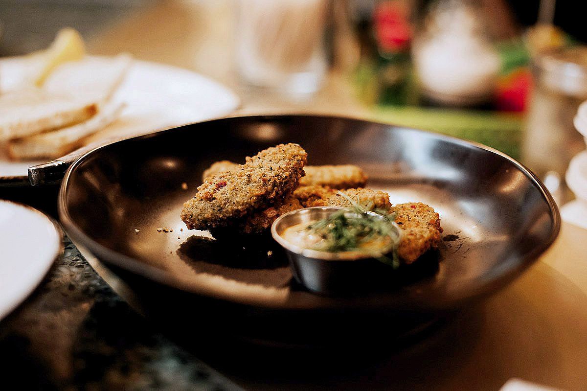 Multiple dark plates with elegant food presentations arranged on a restaurant counter.